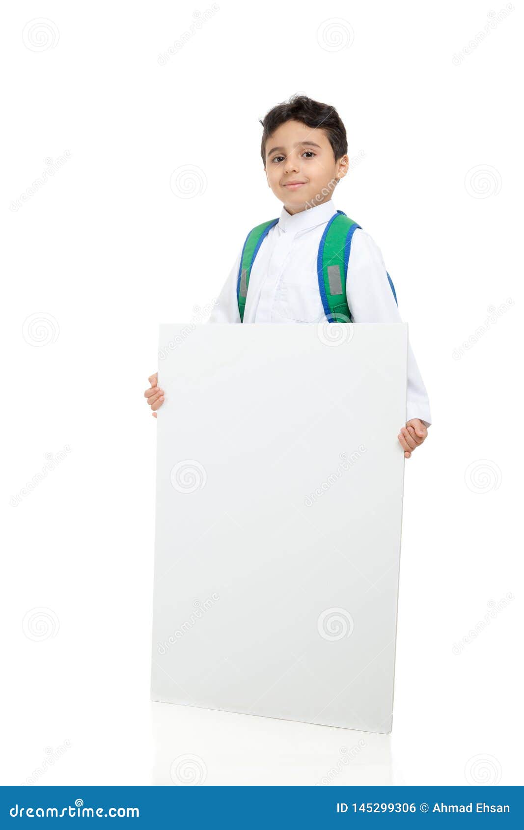 arab school boy holding a big white board with both hands, wearing white traditional saudi thobe and sneakers, raising his hands