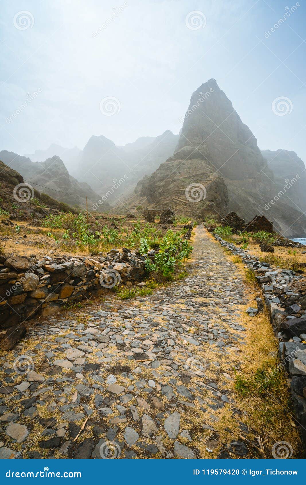 aranhas mountain peak in the valley with house ruins and stony hiking path going up the mountain from ponta do sol to