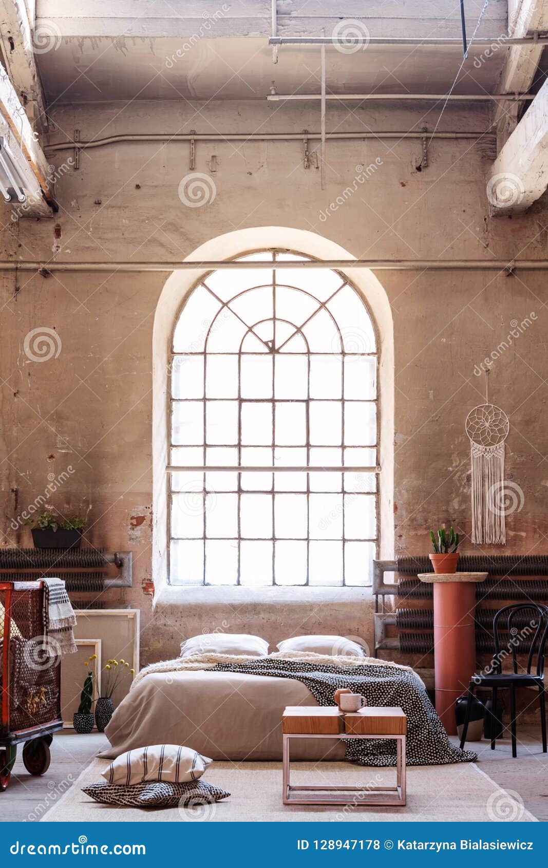 arch window in a wabi sabi bedroom interior with a bed, raw walls and table