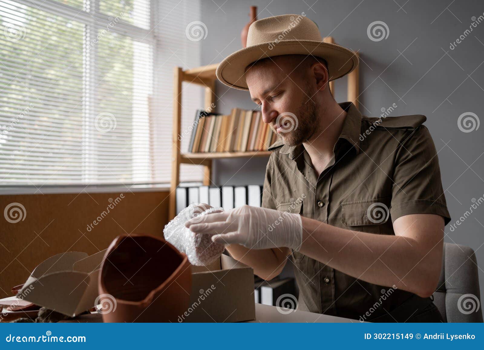 Archaeologist Or Digger In A Hat Working In An Office Packing Antique archaeologist-or-digger-in-a-hat-working-in-an-office-packing-antique