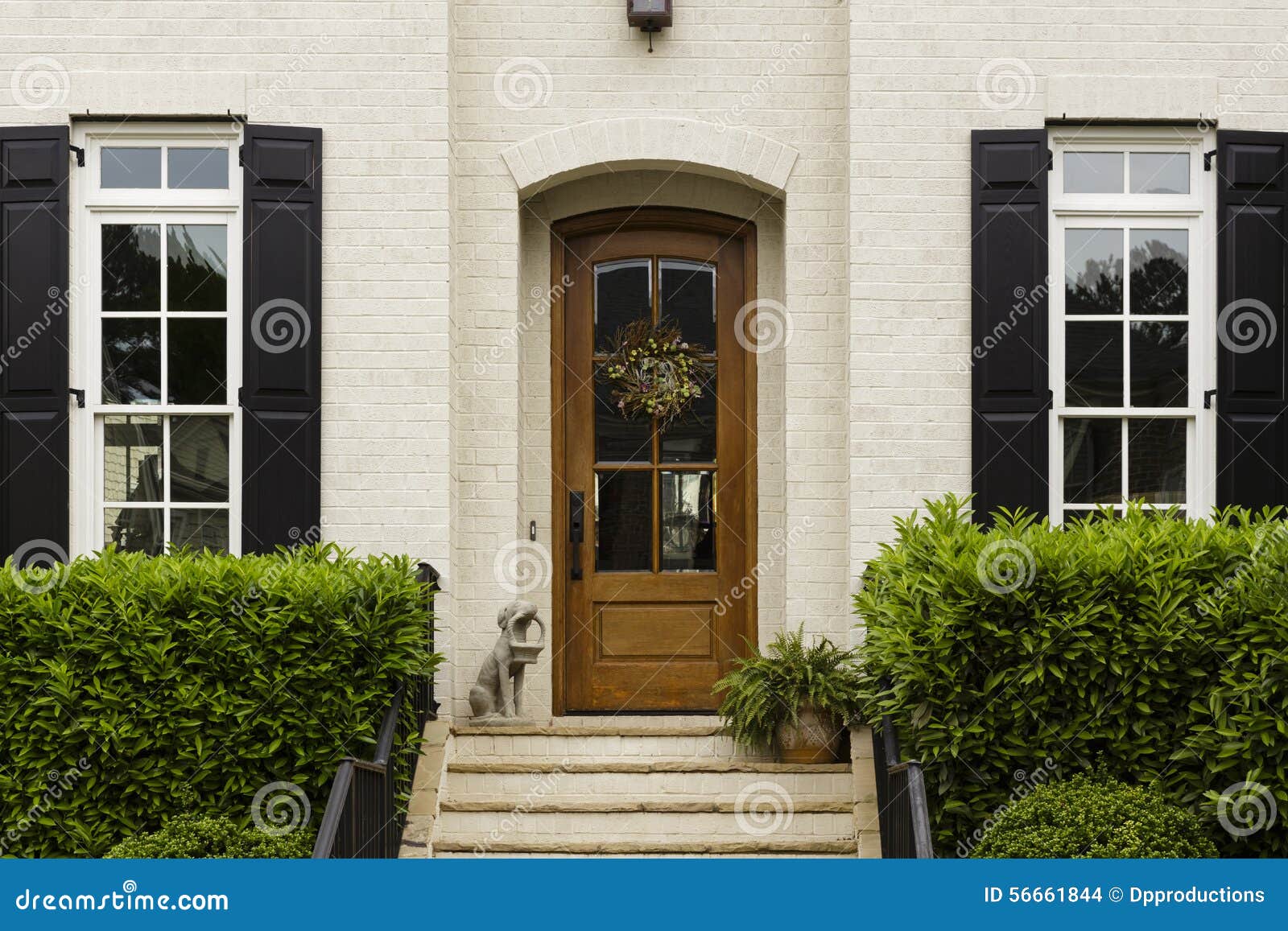 arched front door with statue and shrubs