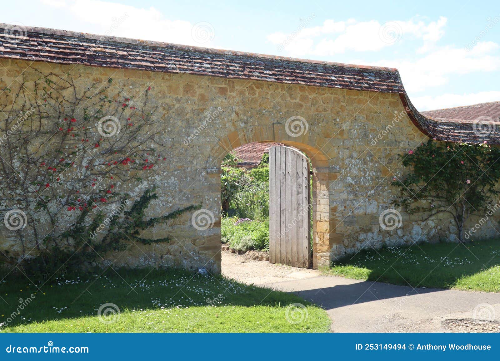 an arched gateway with an old wooden door leads in to the kitchen garden in an old english country manor house