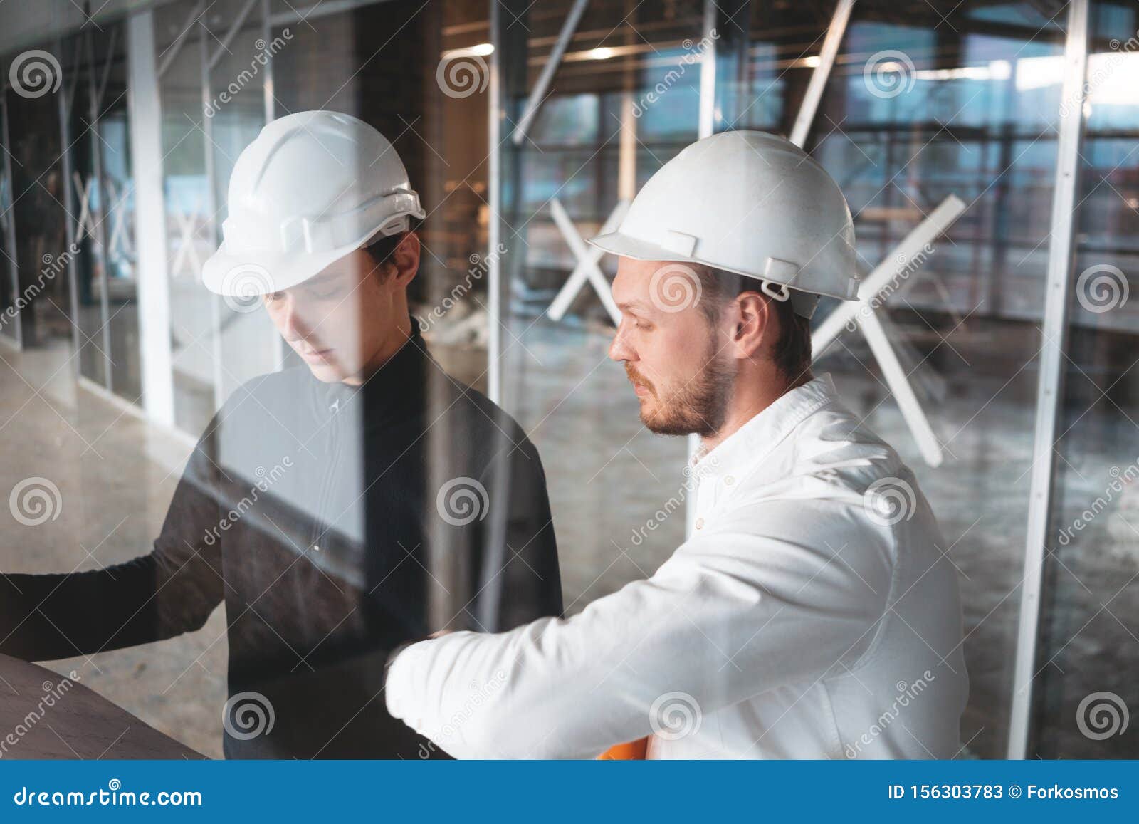 architect and builder lookin on blueprint building under construction