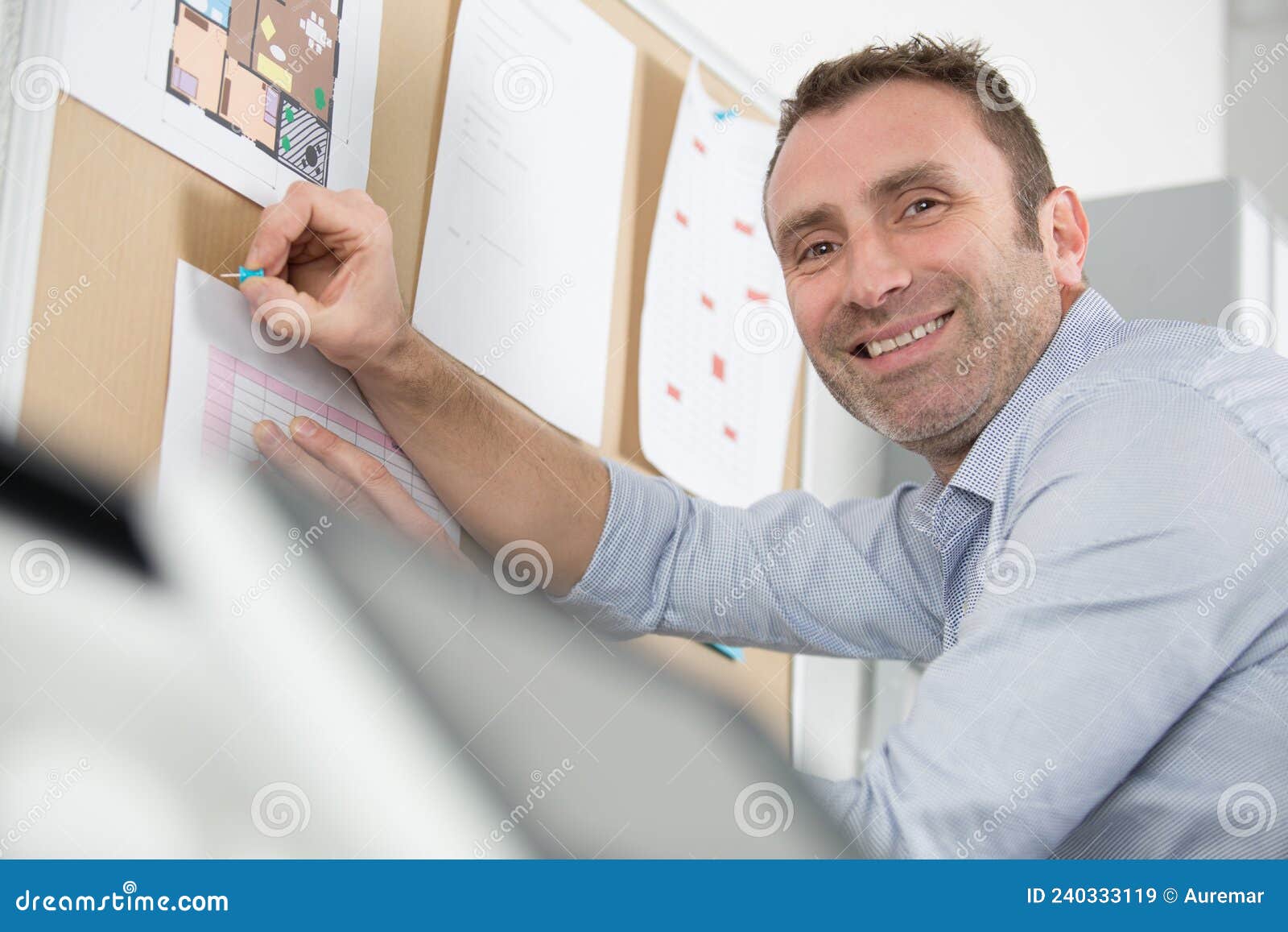 architect smiling and putting blueprint on office board