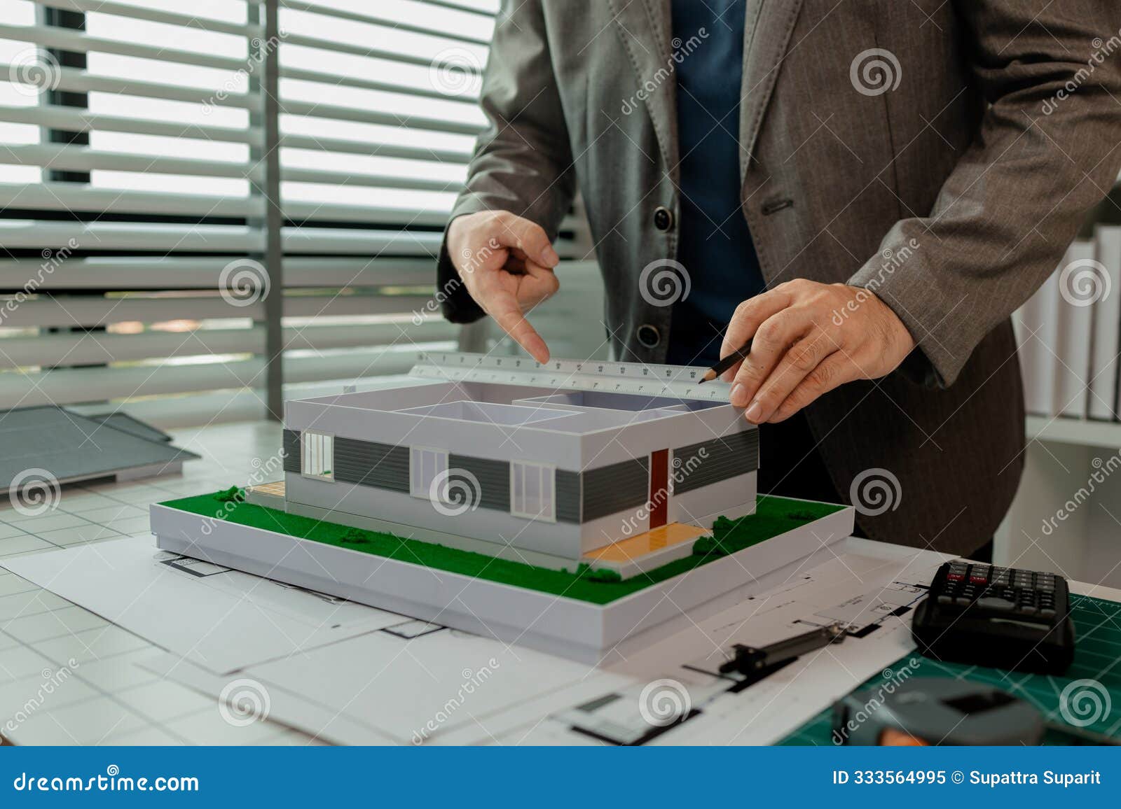 an architect works in the office, an engineer is using a tool to take measurements of a house model so that it matches the