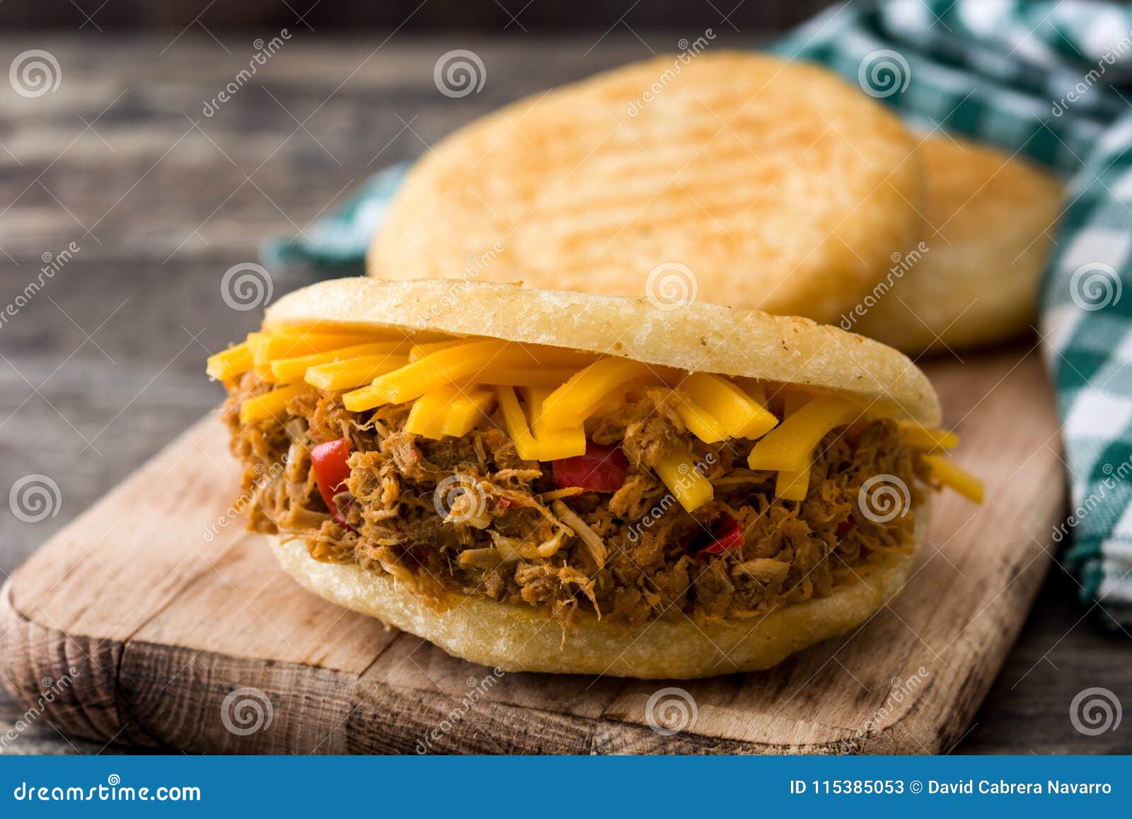 arepa with shredded beef and cheese on wooden background. venezuelan typical food
