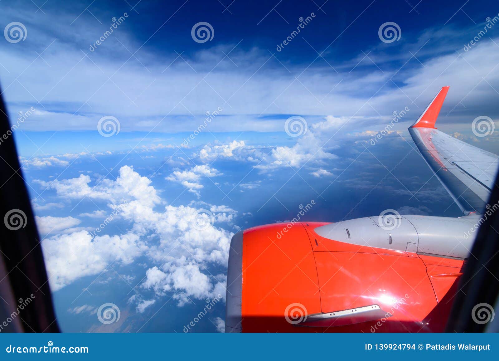 clouds in the sky and cityscapes though airplane window. red aeroplane flying