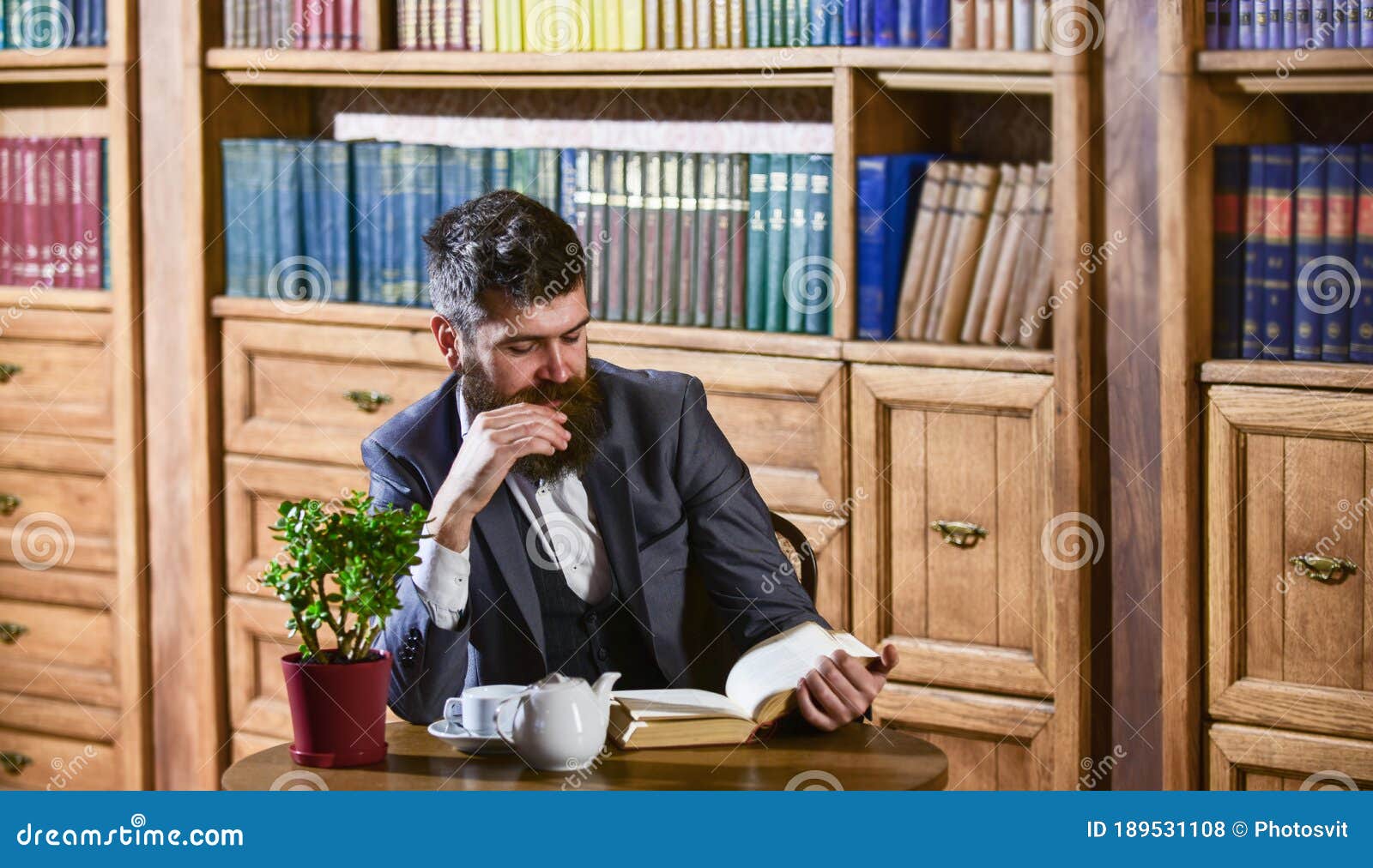 aristocrat on thoughtful face reading book. oldfashioned man near cup