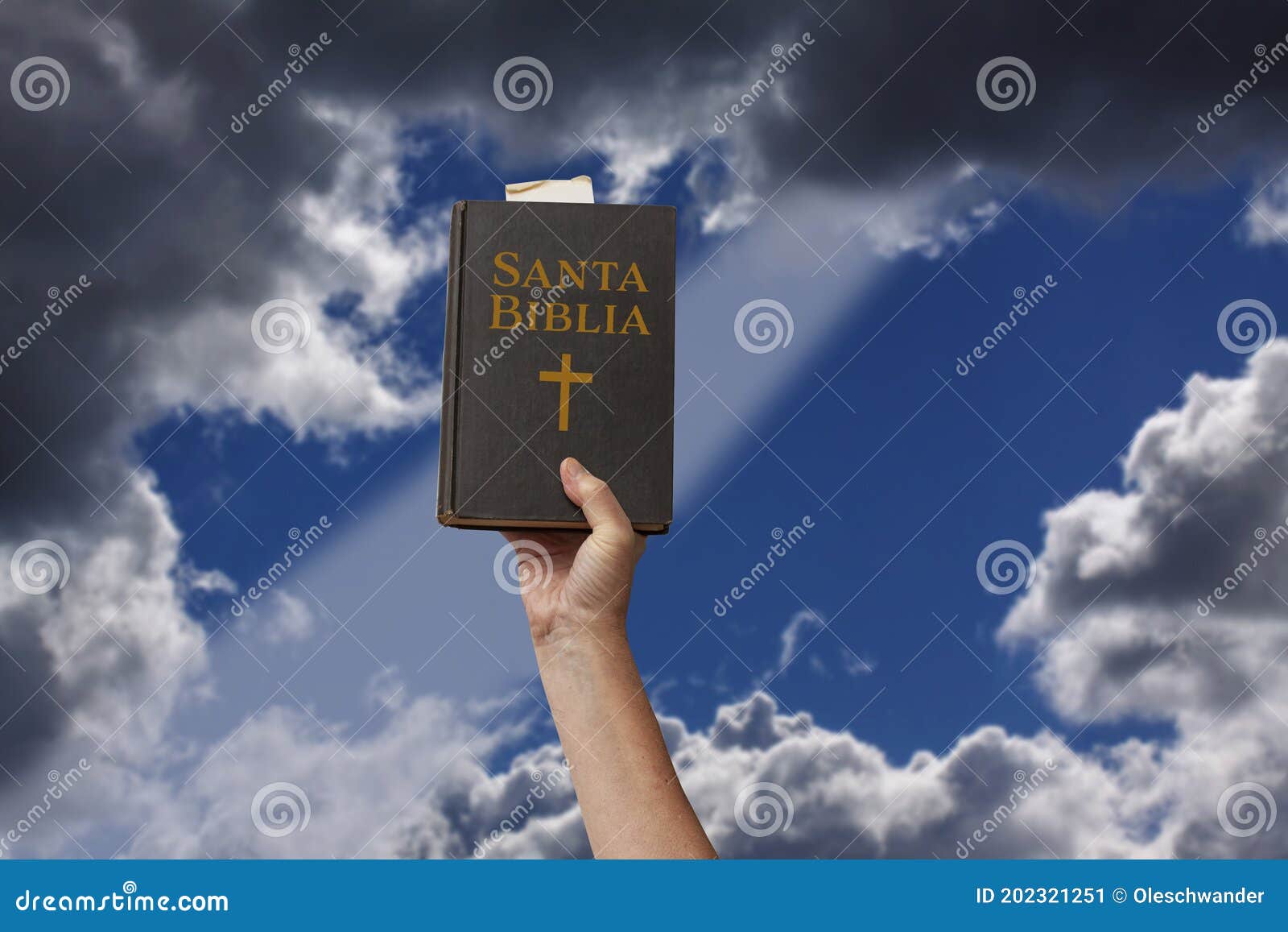 arm raised into the air a hand reaching up and holding the holy bible in spanish santa biblia. ray of light coming through dramati