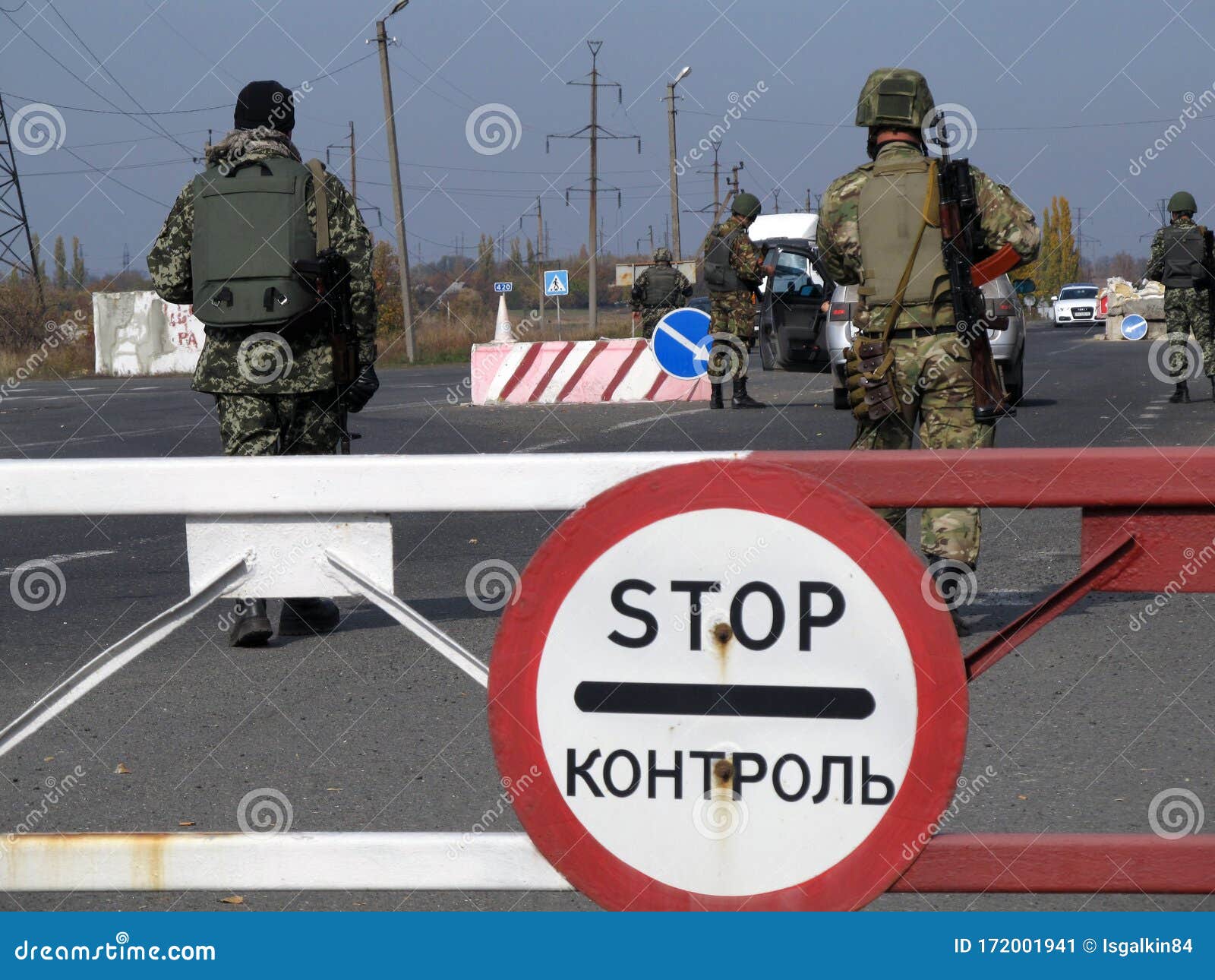 armed ukrainian border guards check vehicles on  the security checkpoint. war in donbass. the inscription on the road sign - stop.