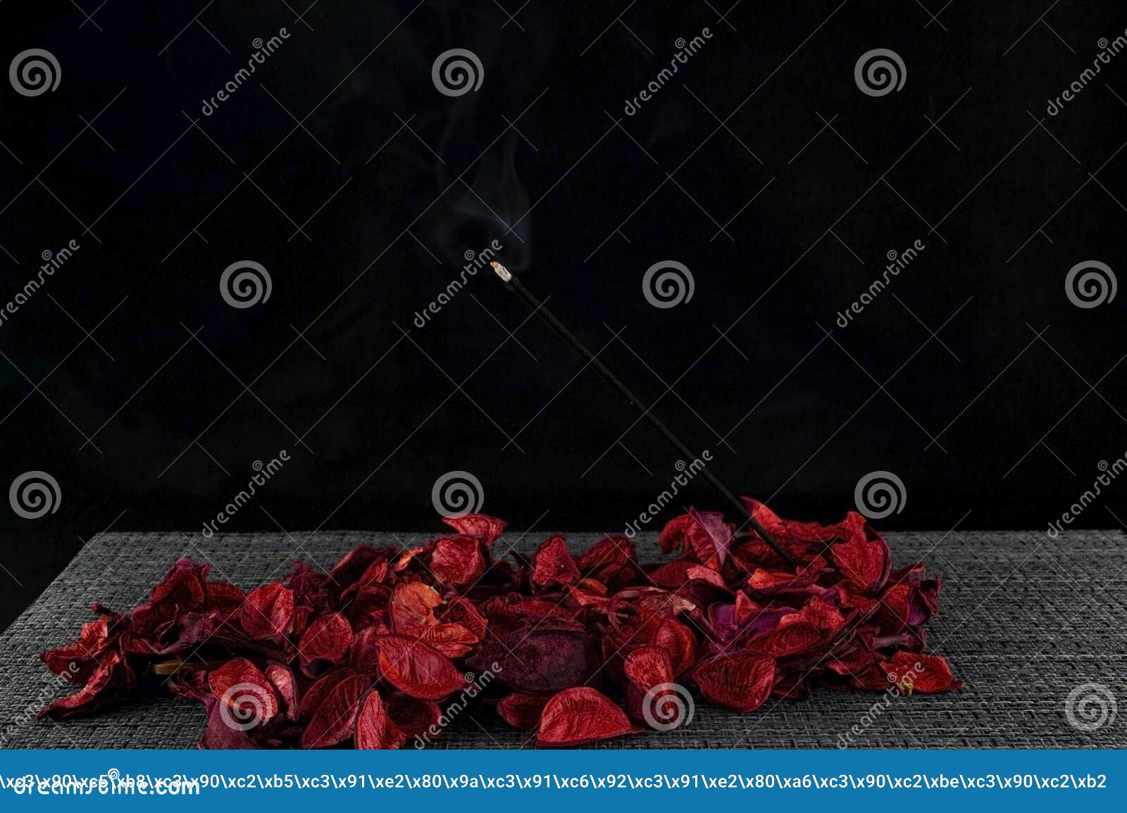 the aroma stick burns over the red petals.