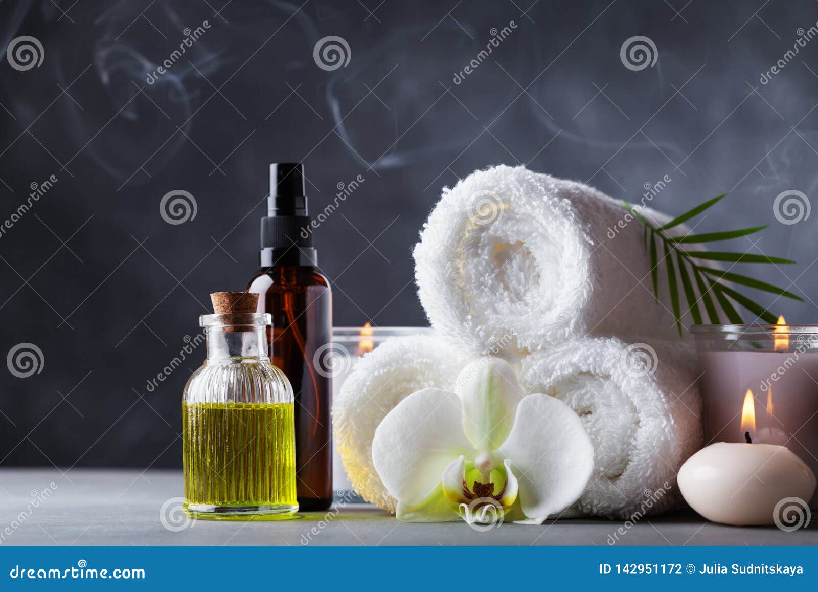 aromatherapy, spa, beauty treatment and wellness background with massage oil, orchid flowers, towels, cosmetic products