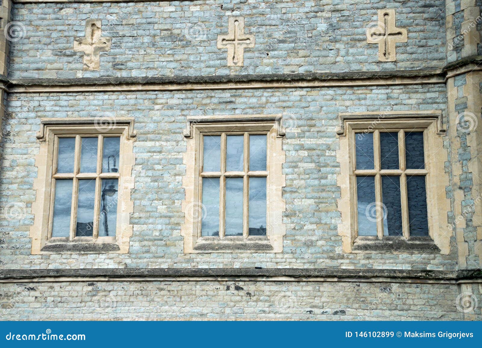 Arquitetura inglesa tradicional velha, três janelas e cruzes acima