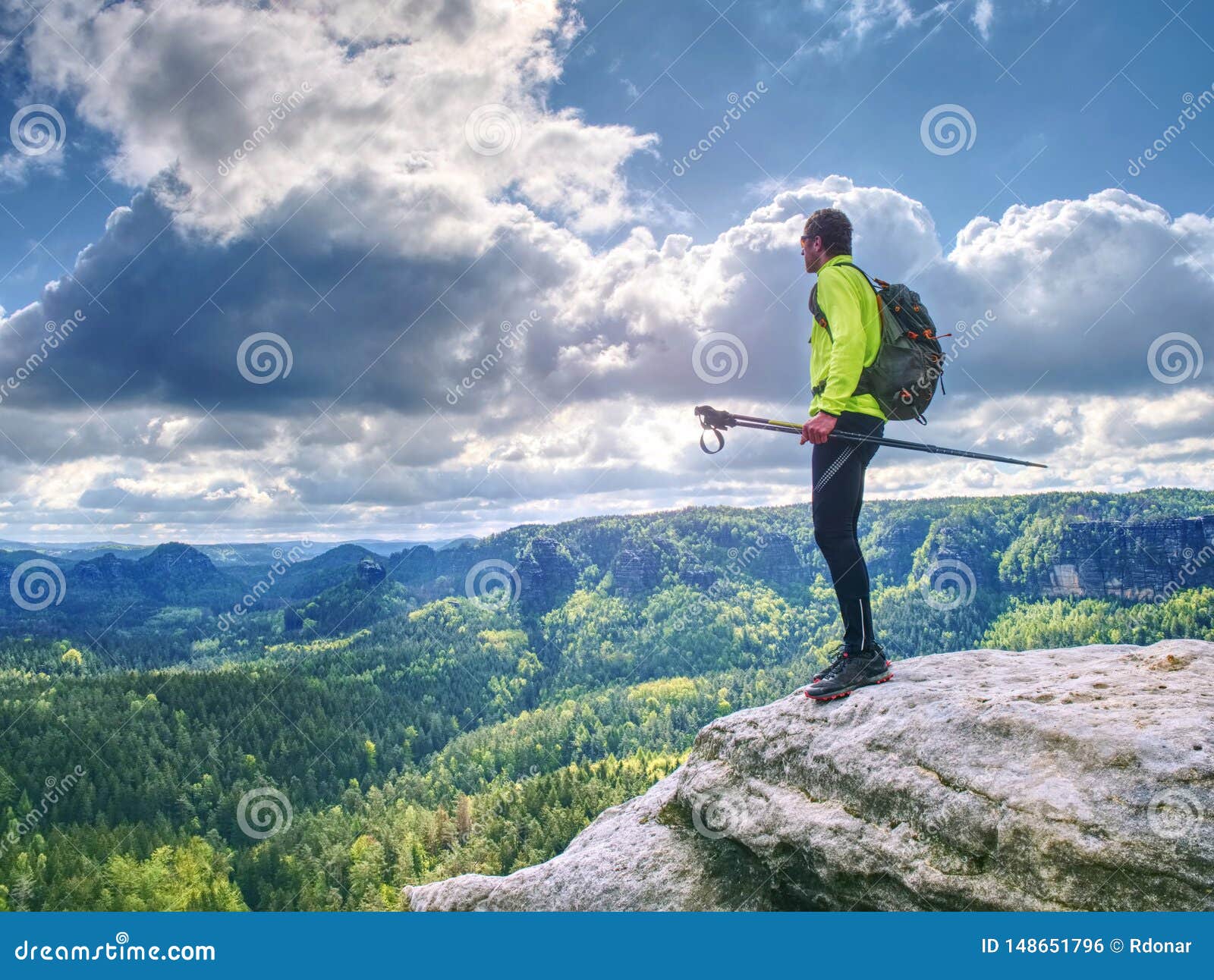 Man trail runner stop on mountain top for relax. Trail athlete in light green lerzey and black leggings on the trail with long deep valley on the background