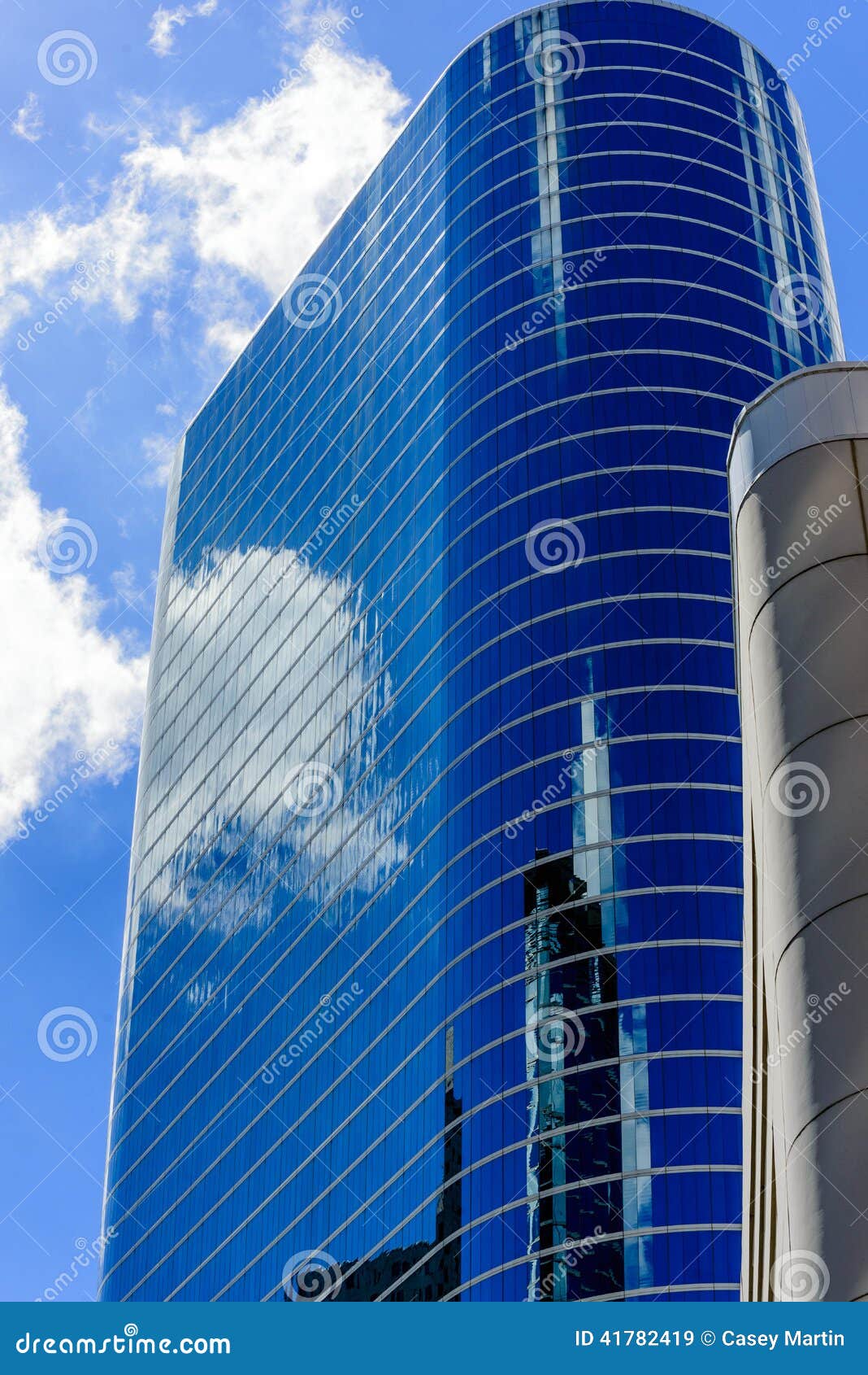 Arranha-céus de vidro oval curvado em houston do centro com reflexão do céu