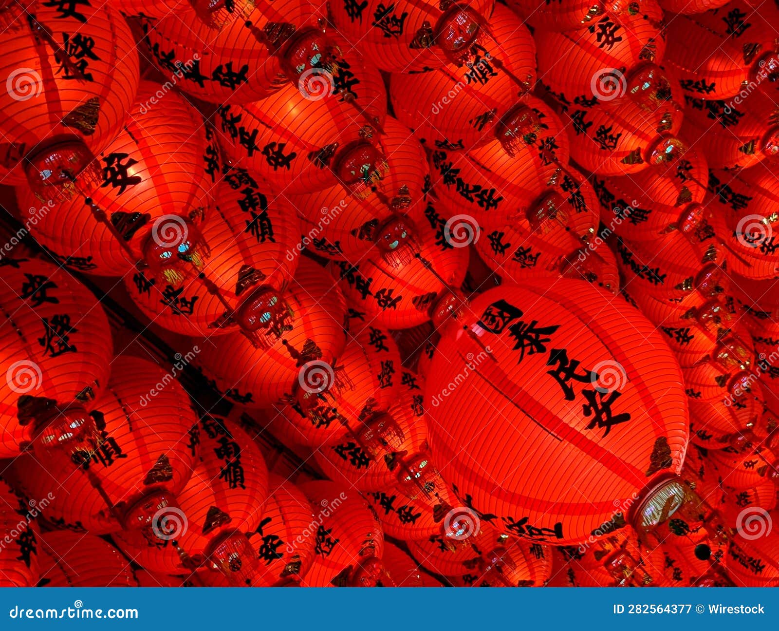 an array of vibrant red taiwanese lanterns hanging from ceiling, labeled with chinese hieroglyphs