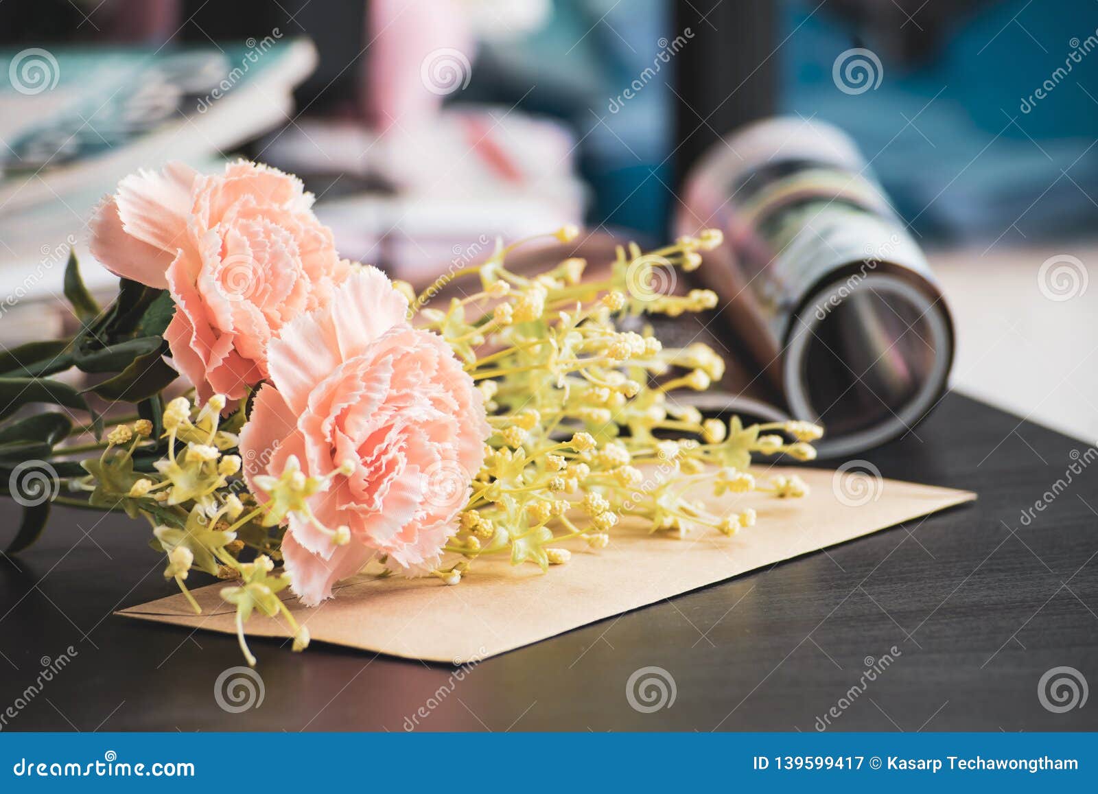 Artificial Flowers on Black Laptop Desk with Magazines Background