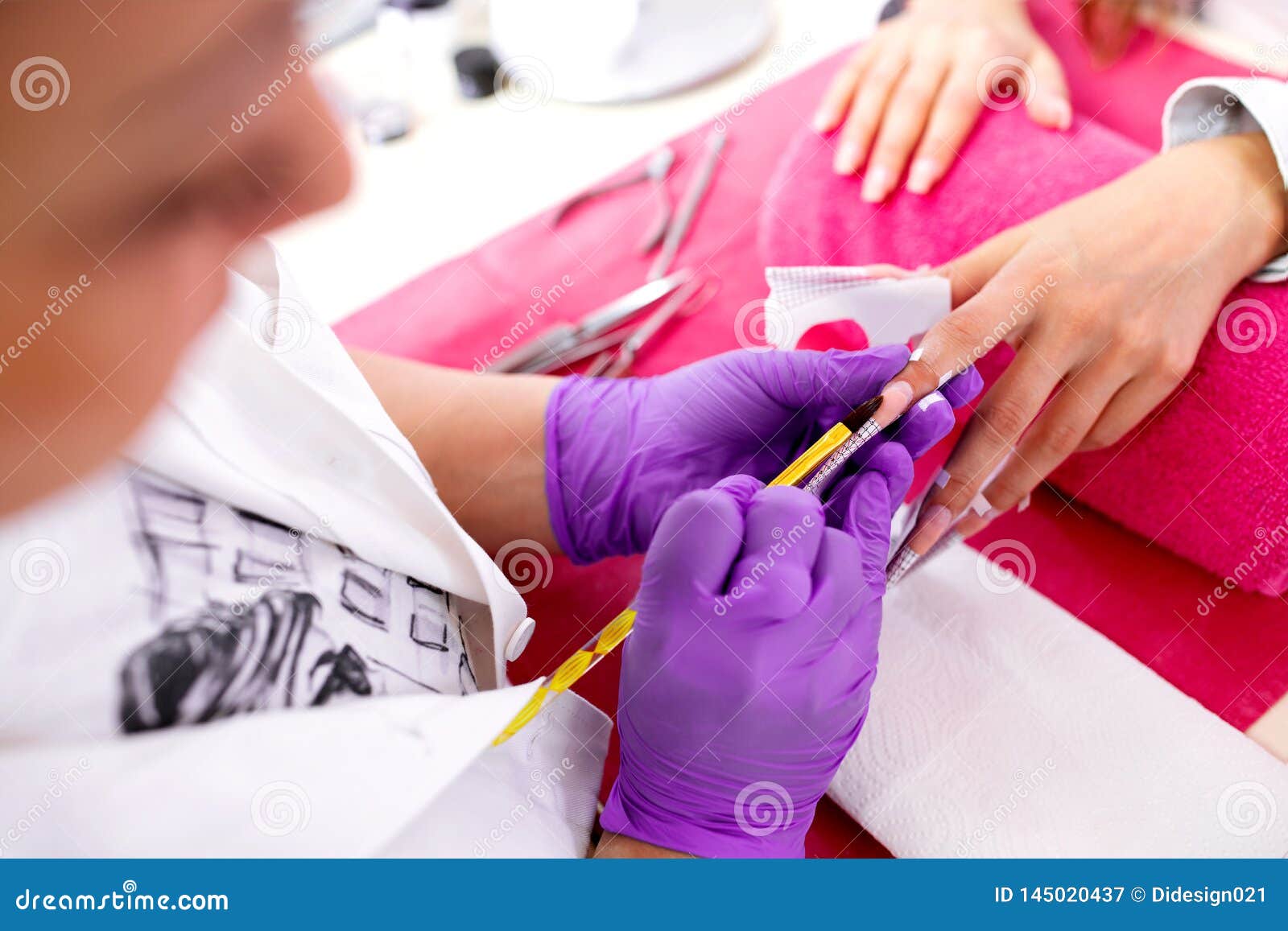 artificial nail enhancement being applied by the hands of an experienced manicure salon worker