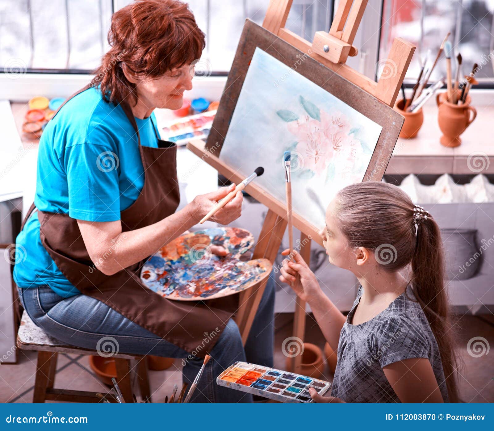 artist painting easel in studio. authentic grandmother and kids.