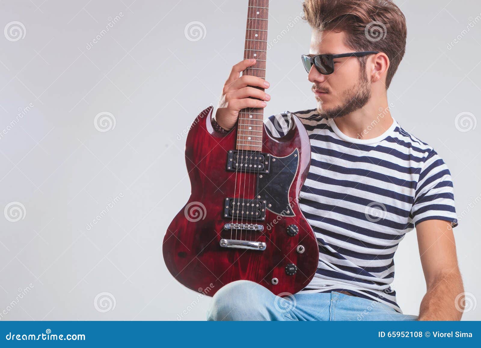 Premium Photo | A young musician striking a pose while holding his guitar