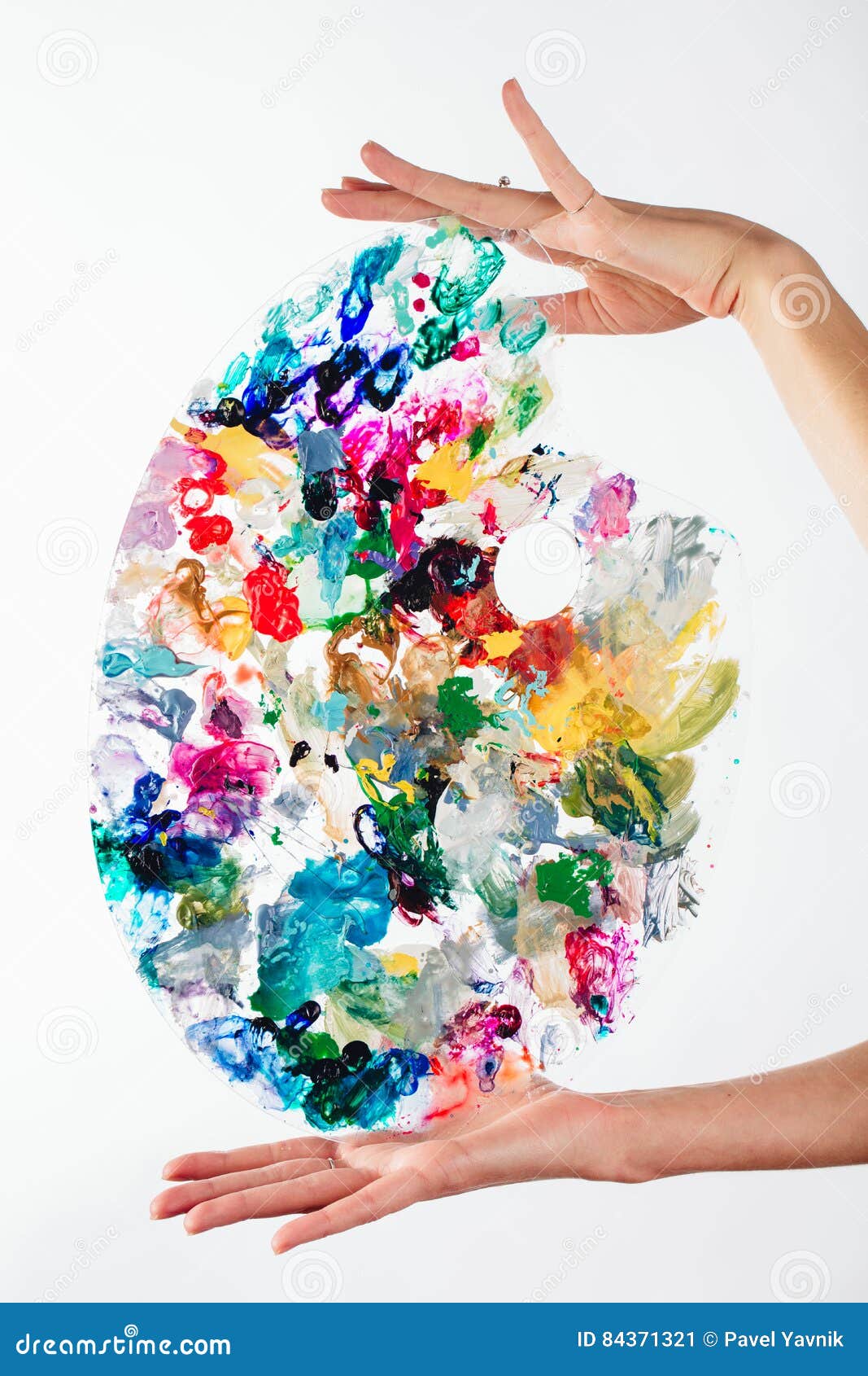 The artist`s palette stained with paint. On a white background, Gently hold both hands, unrecognized.