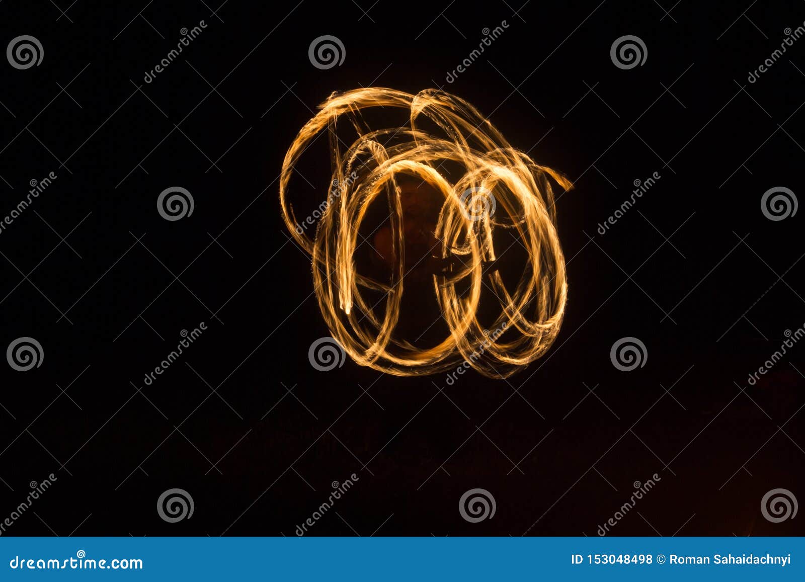 The Artist Shows a Fire Show at Night Spinning Torches, Circles of Fire and Loops Stock Photo
