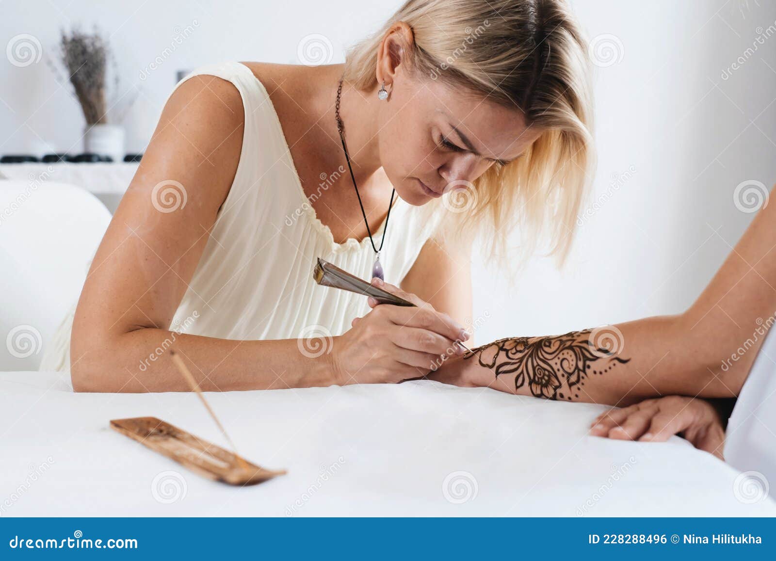Artista aplicando tatuagem de henna mehndi na mão feminina
