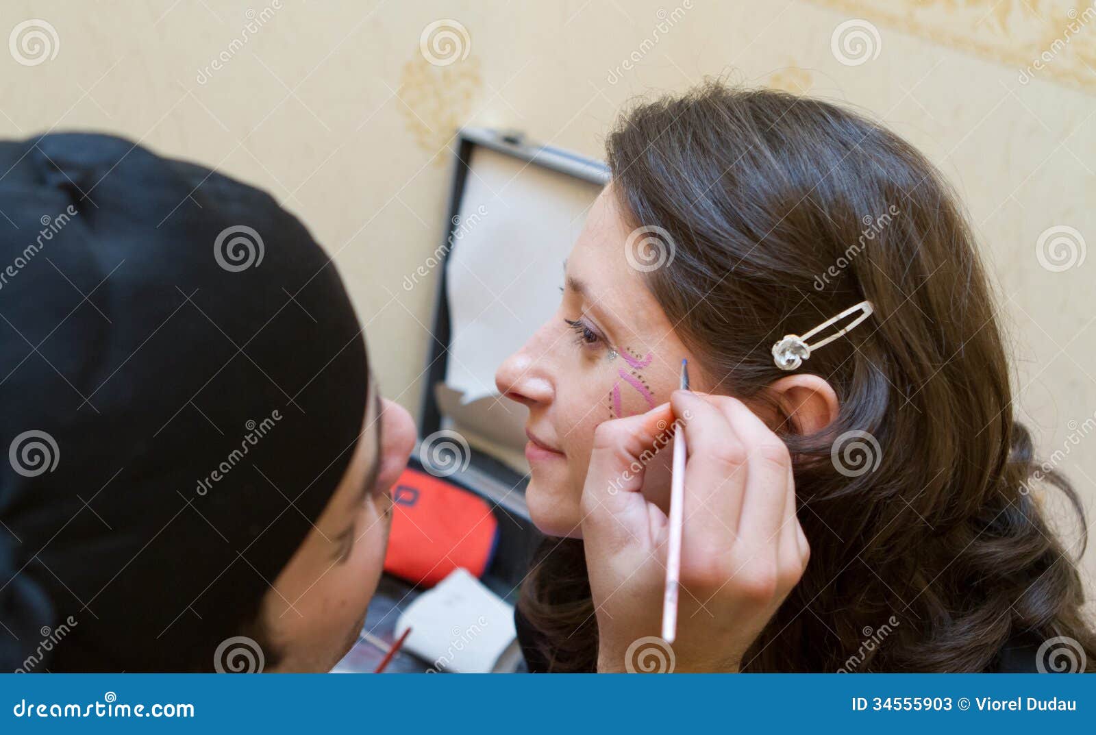 Mujer que hace que su cara sea pintada por el artista de la pintura de la cara