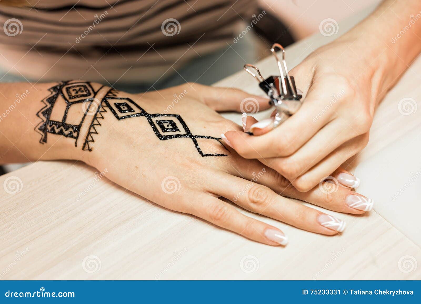 Artista aplicando tatuagem de henna mehndi na mão feminina