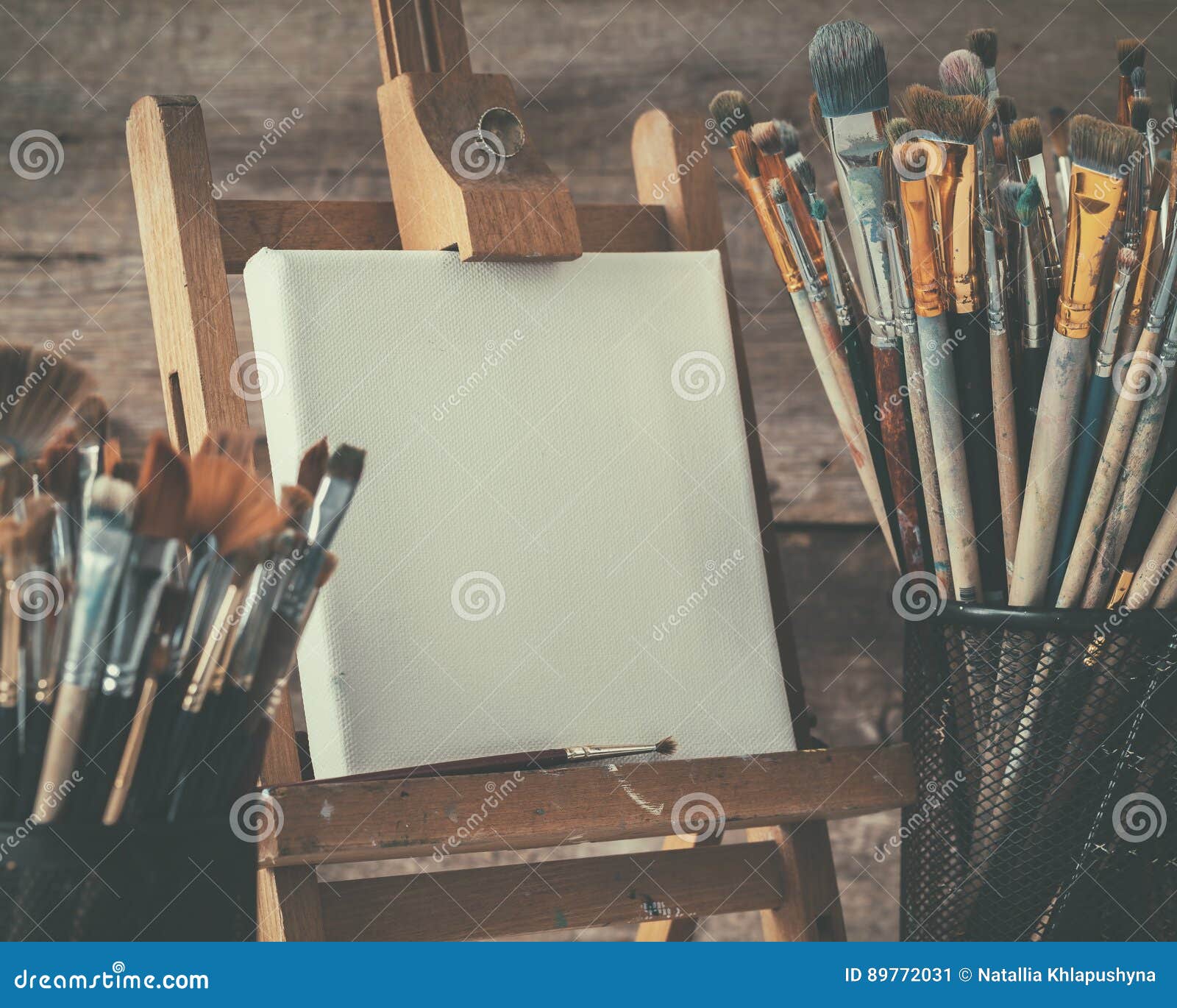 artistic equipment: artist canvas on easel and paint brushes.