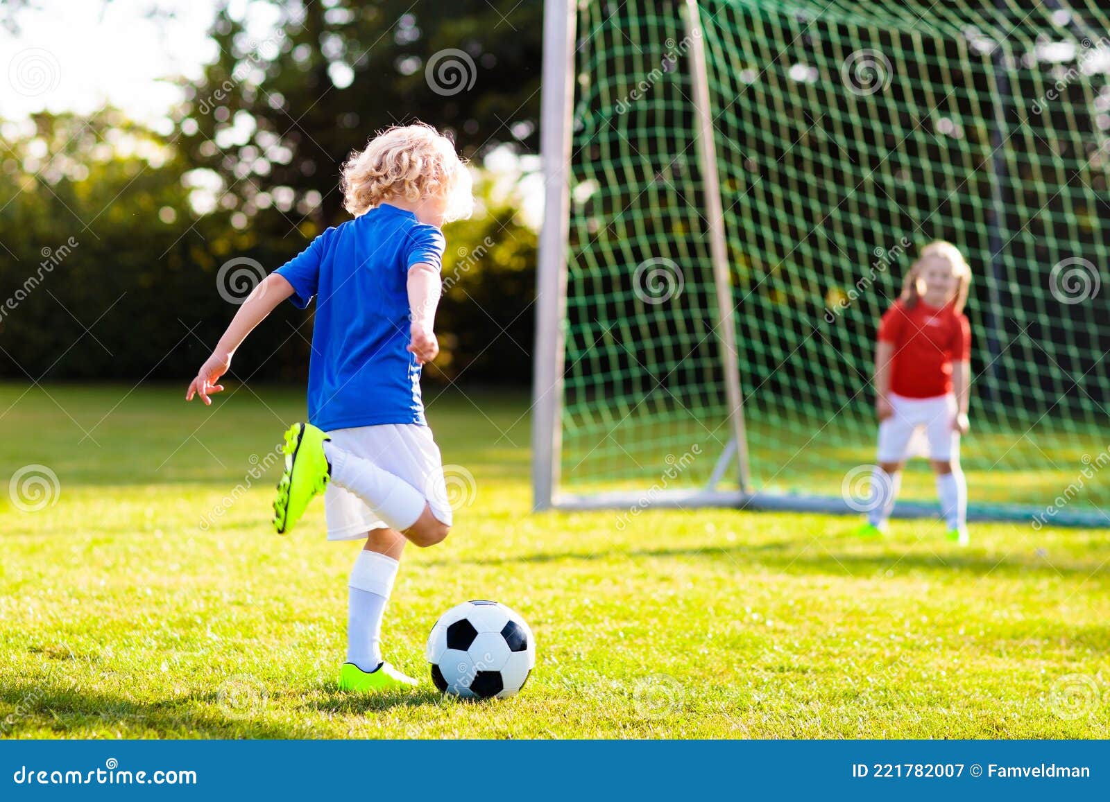 As crianças jogam futebol no campo ao ar livre. as crianças marcam um gol  no jogo