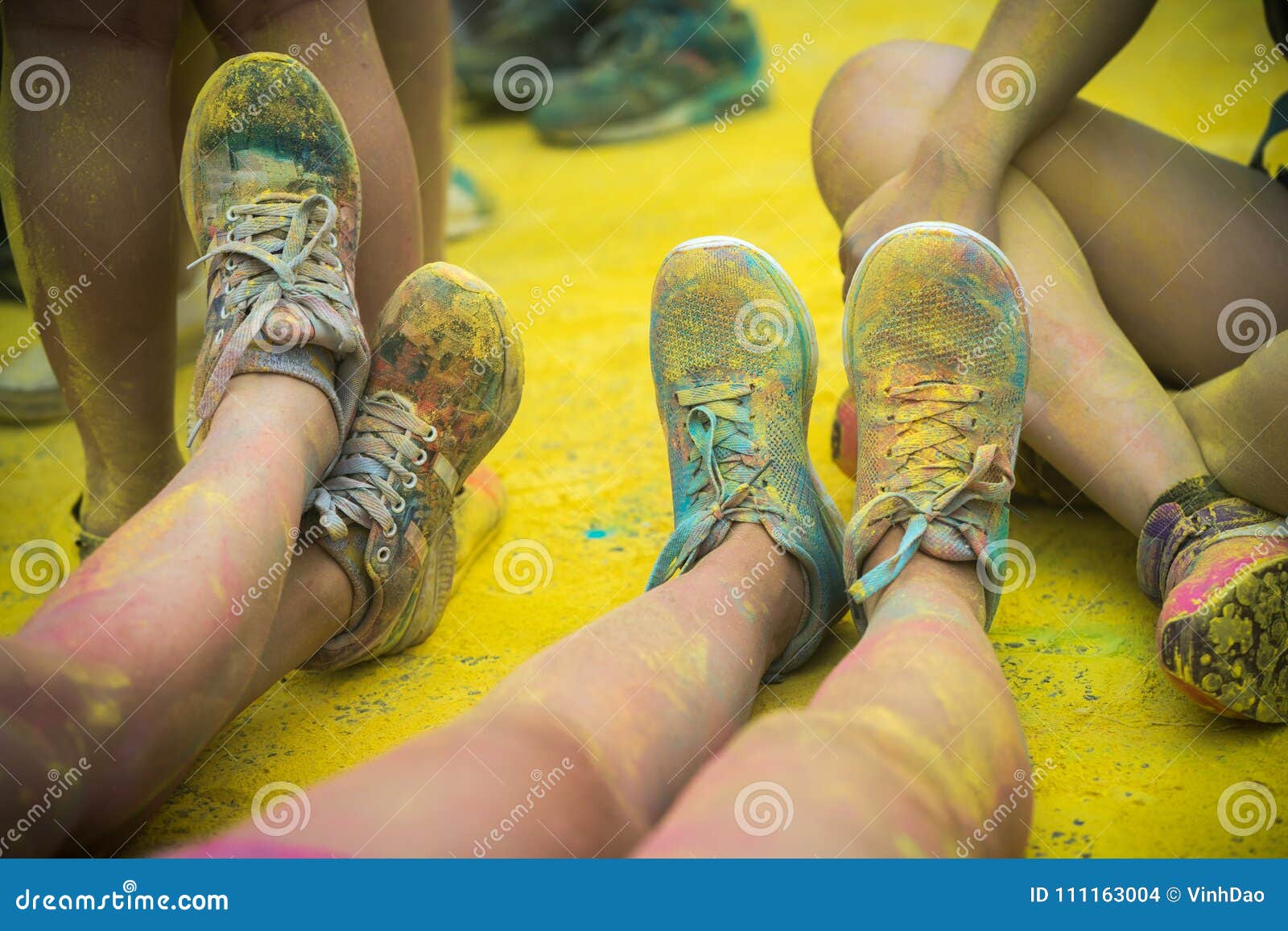 As sapatas e os pés coloridos dos adolescentes no evento da corrida da cor