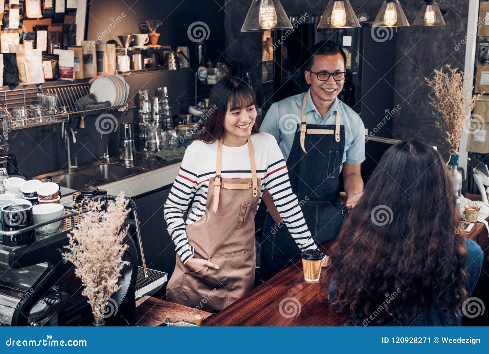 asia barista waiter and waitress take order from customer in coffee shop,two cafe owner writing drink order at counter