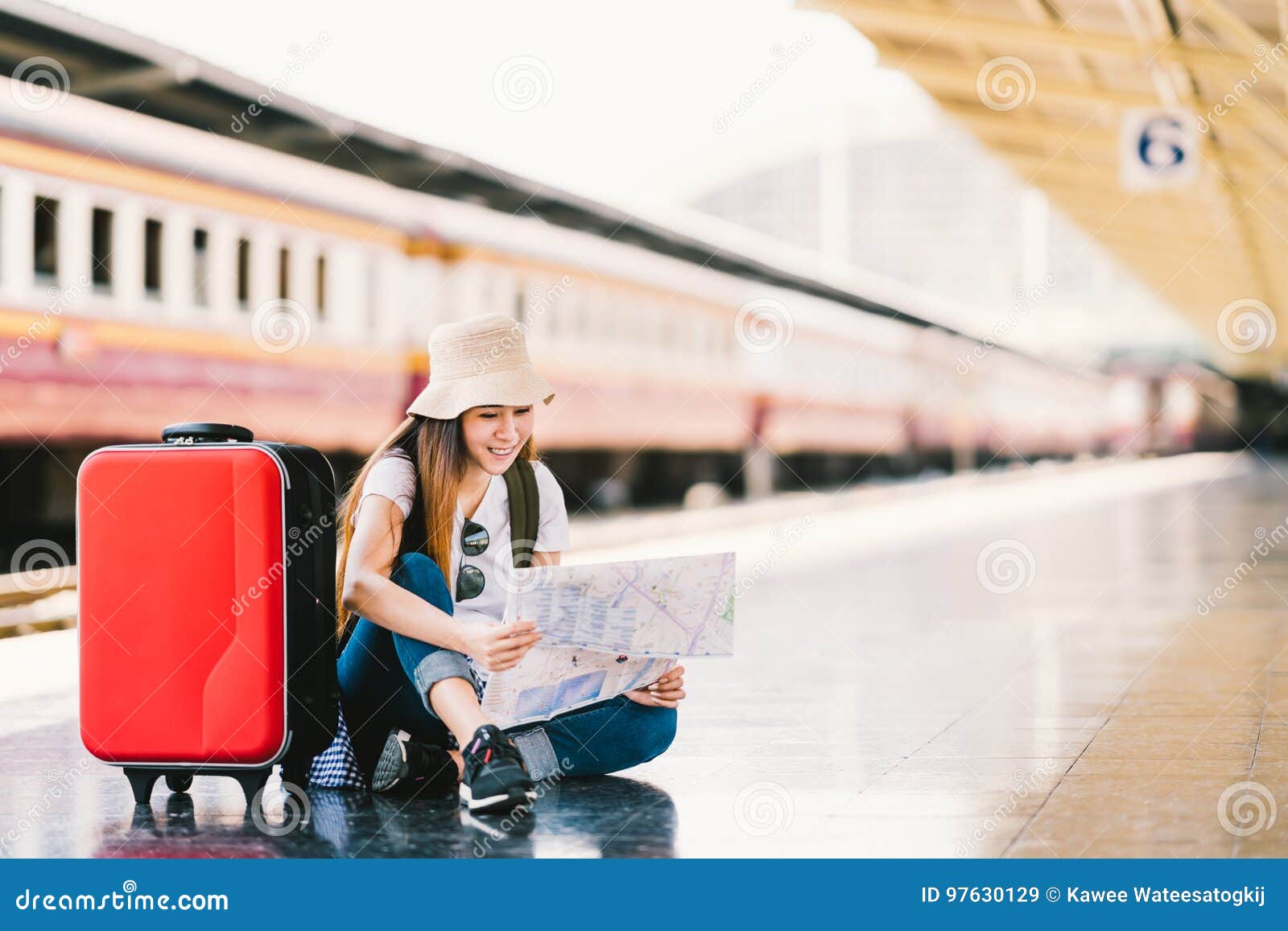 asian backpack traveler woman using generic local map, siting alone at train station platform with luggage
