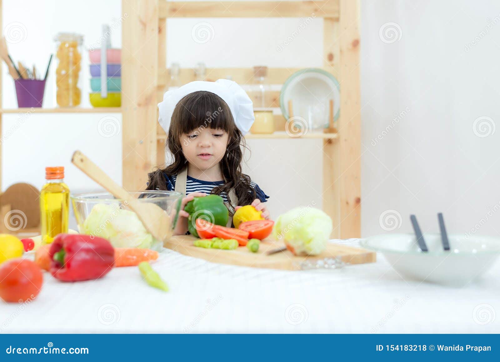 asian beautiful kid girl cooking and cutting vegetables on kitchen, so happy and relax for leaning and education cook food.