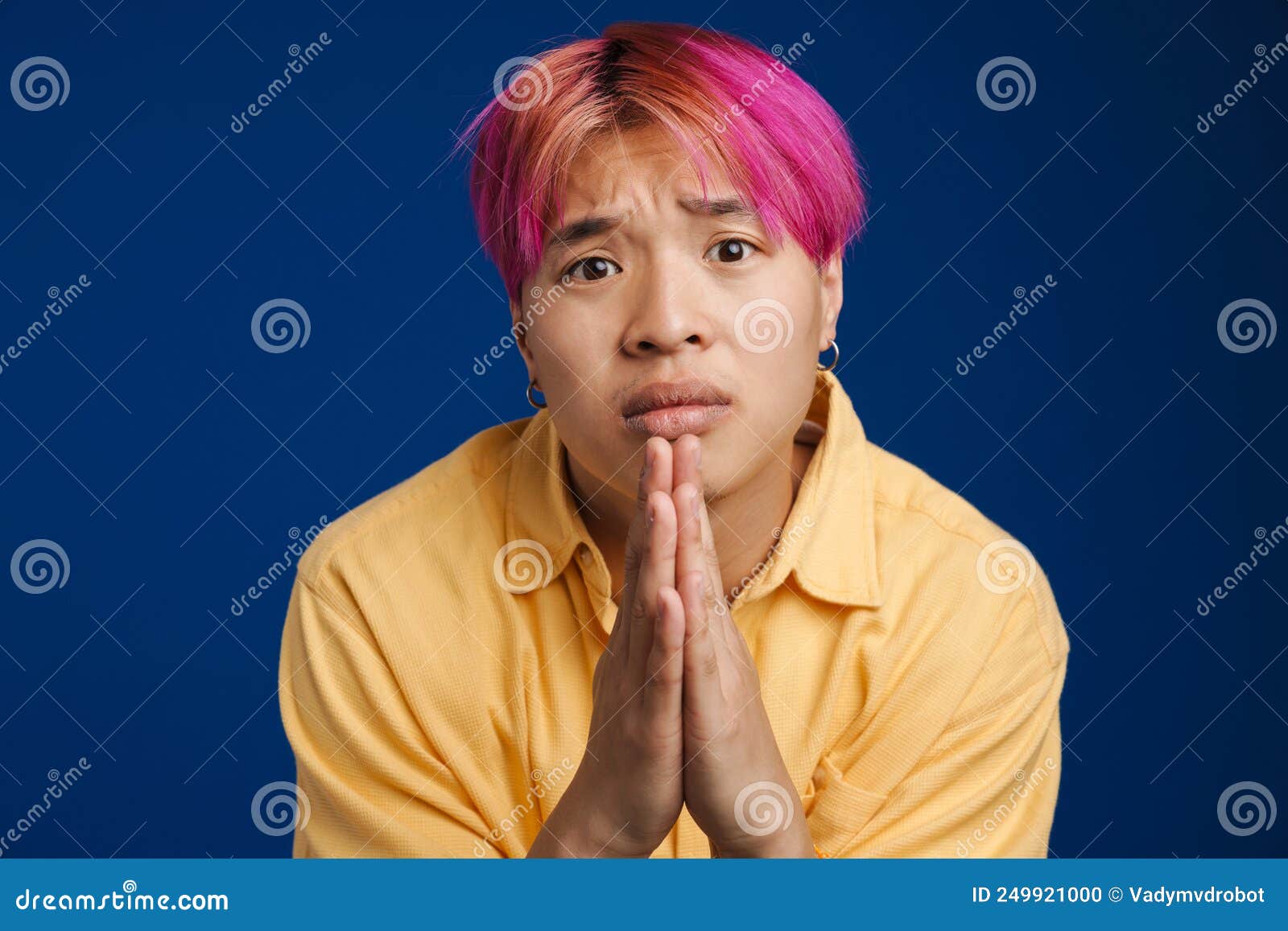 asian boy with pink hair frowning while payer gesture