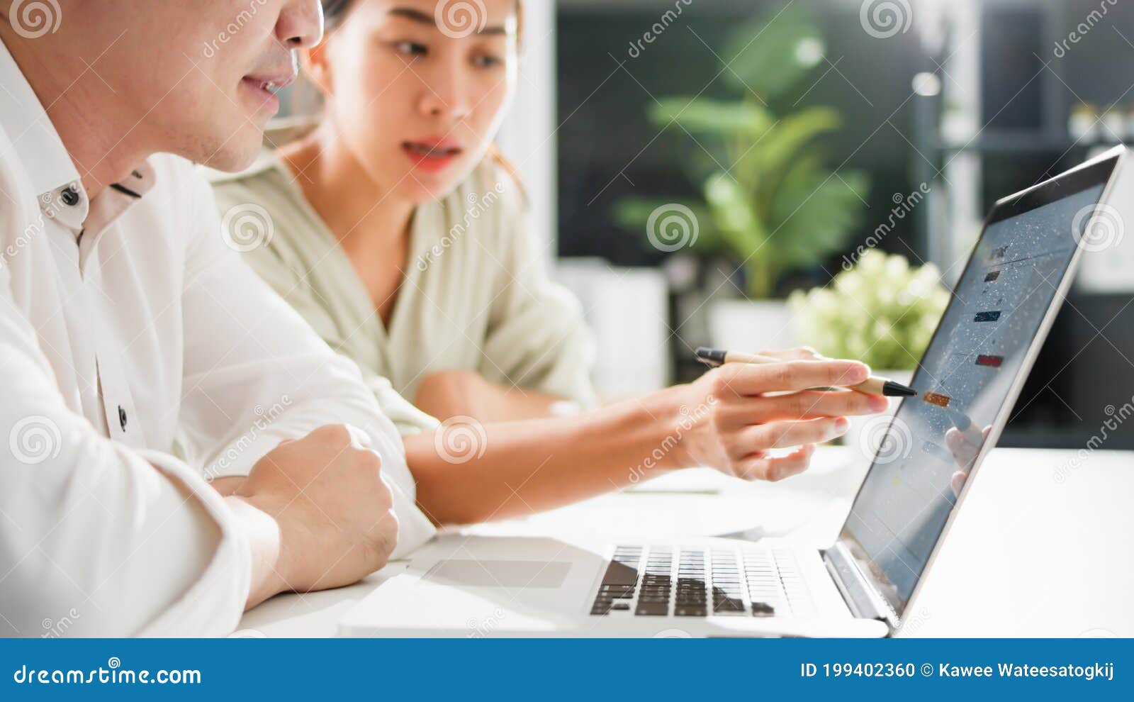 asian business man present and explain work to female colleague, using laptop computer in office at night