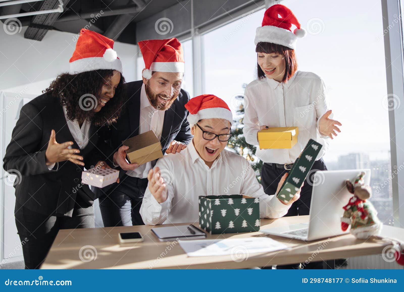 asian businessman in santa hat unpacks a christmas present from multinationals colleagues