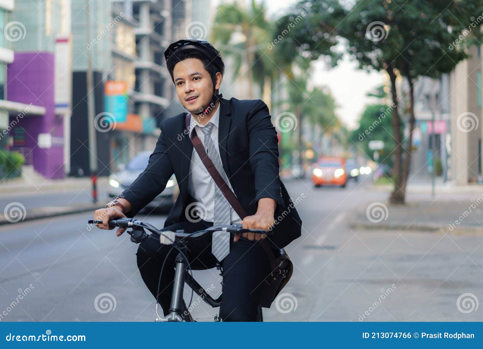 asian businessman in a suit is riding a bicycle on the city streets for his morning commute to work. eco transportation concept