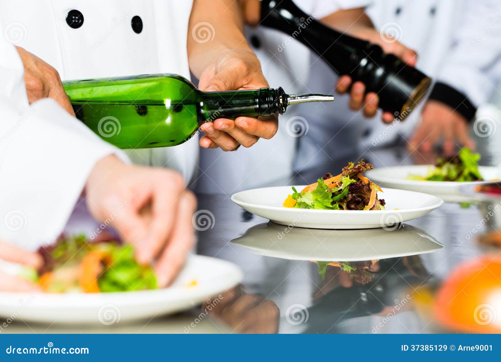 Asian Chef in restaurant kitchen cooking. Asian Indonesian chef along with other cooks in restaurant or hotel commercial kitchen cooking, finishing dish or plate