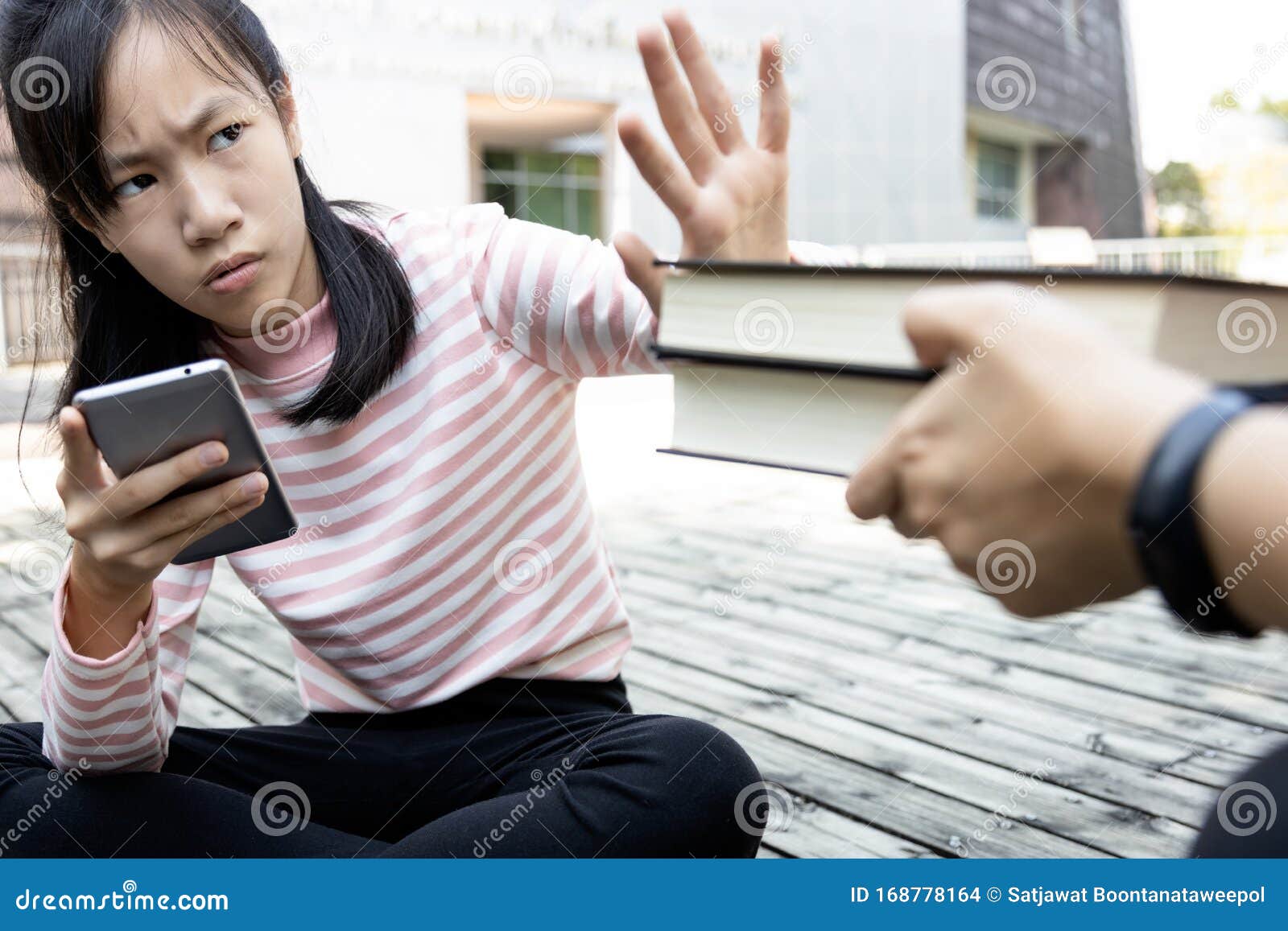 asian child girl is avoiding reading book,she wants to use a mobile phone,addicted to smartphone,teenage student is refusing to