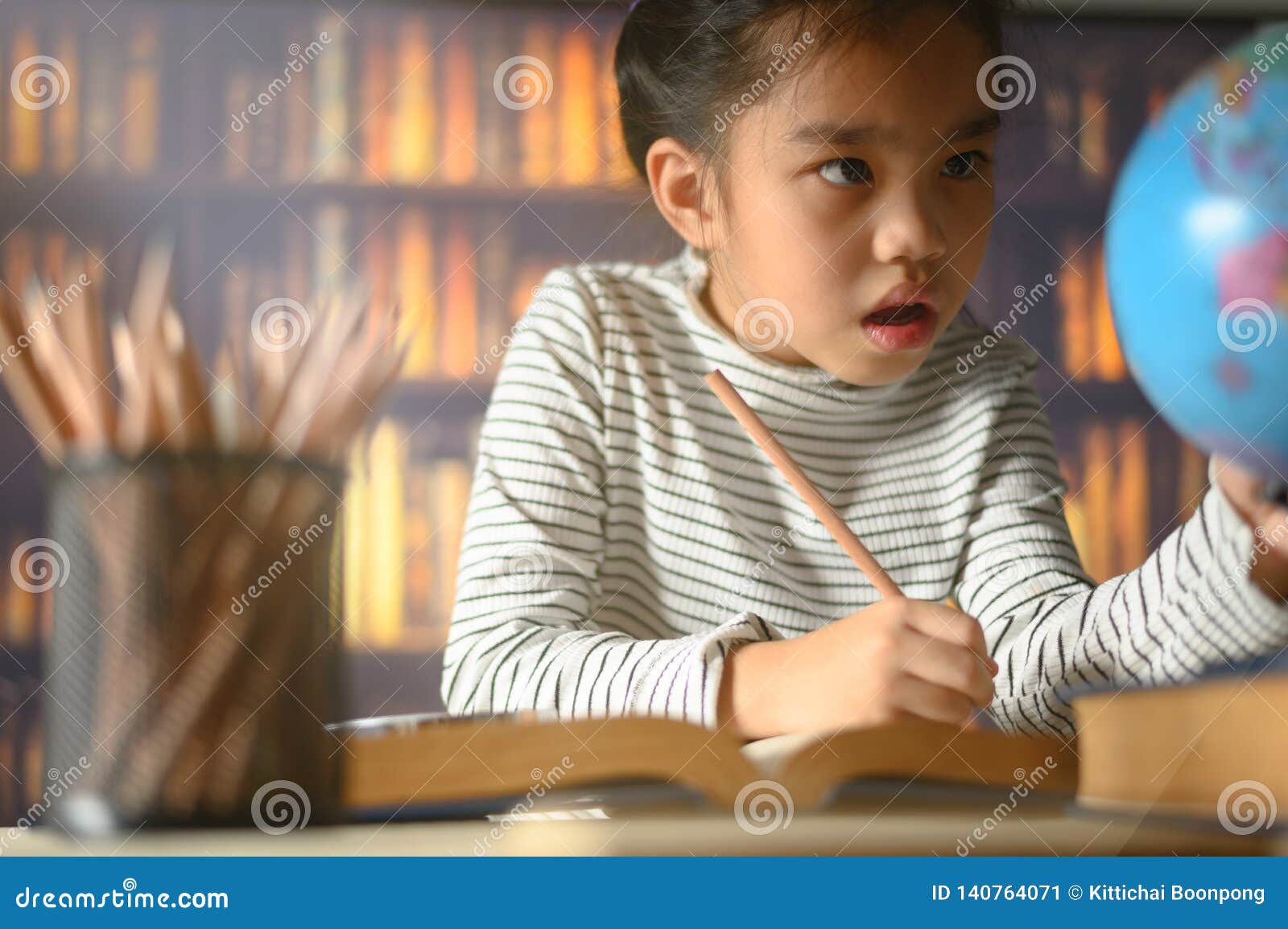 asian child girl industrious is sitting at a desk indoors. kid is learning in home