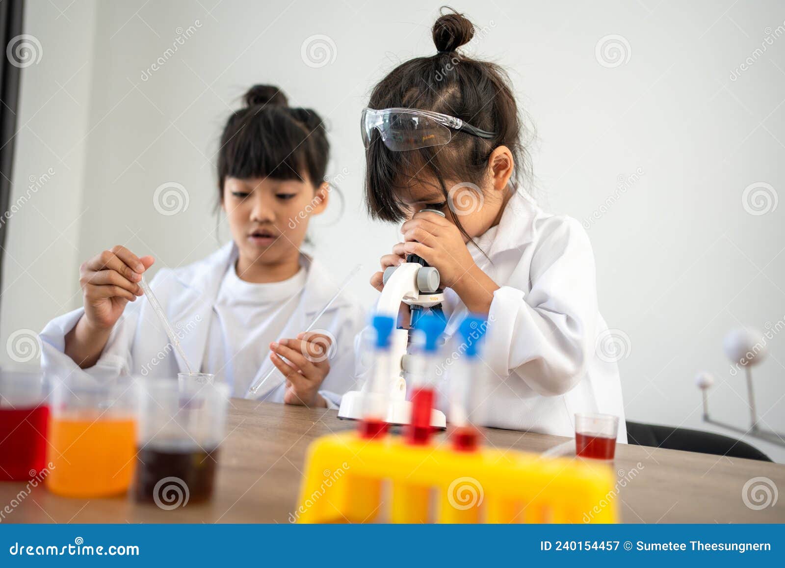 Asian Children in Lab Coat Using a Microscope for a Science Experiment