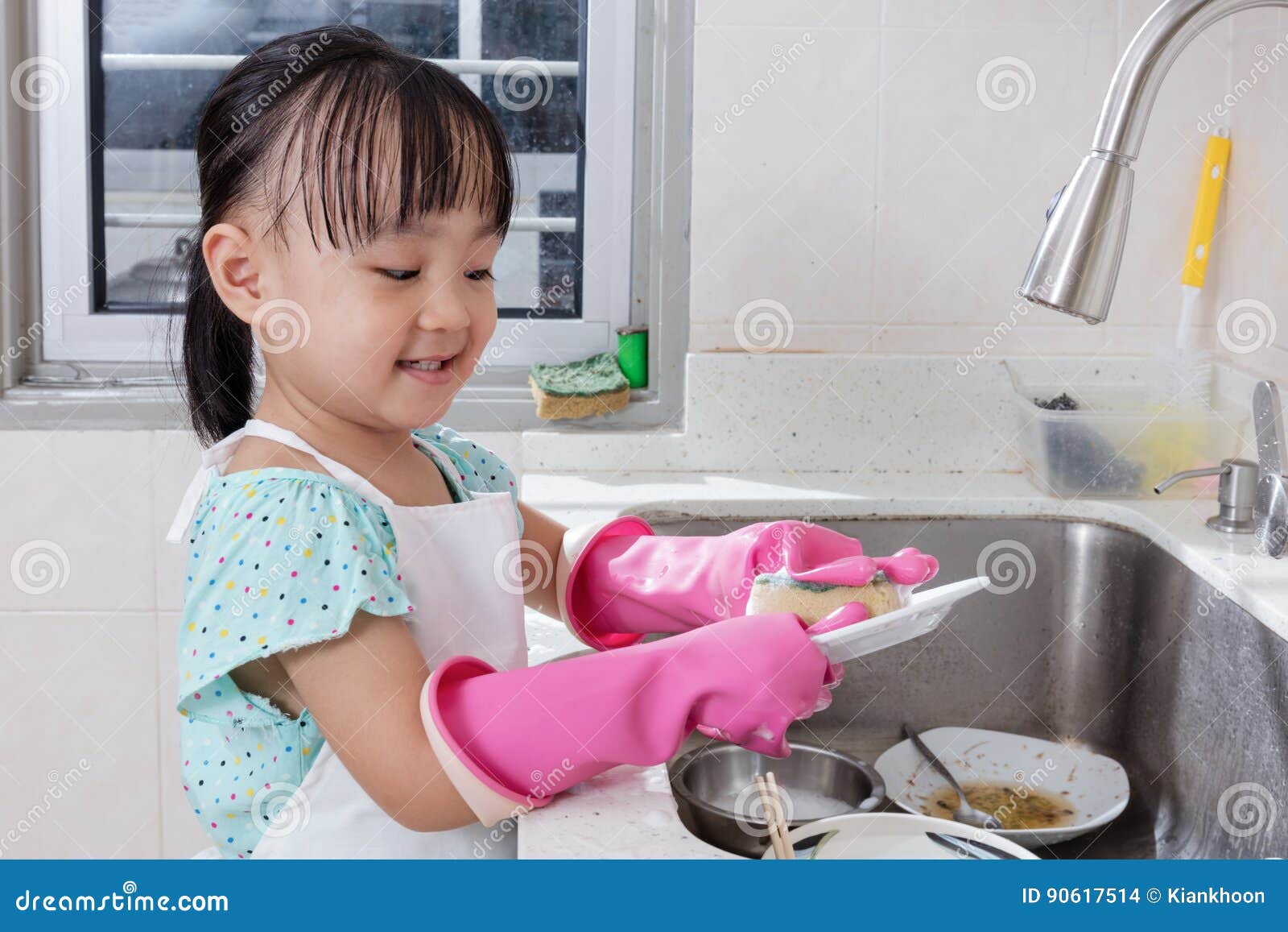 asian chinese little girl washing dishes in the kitchen
