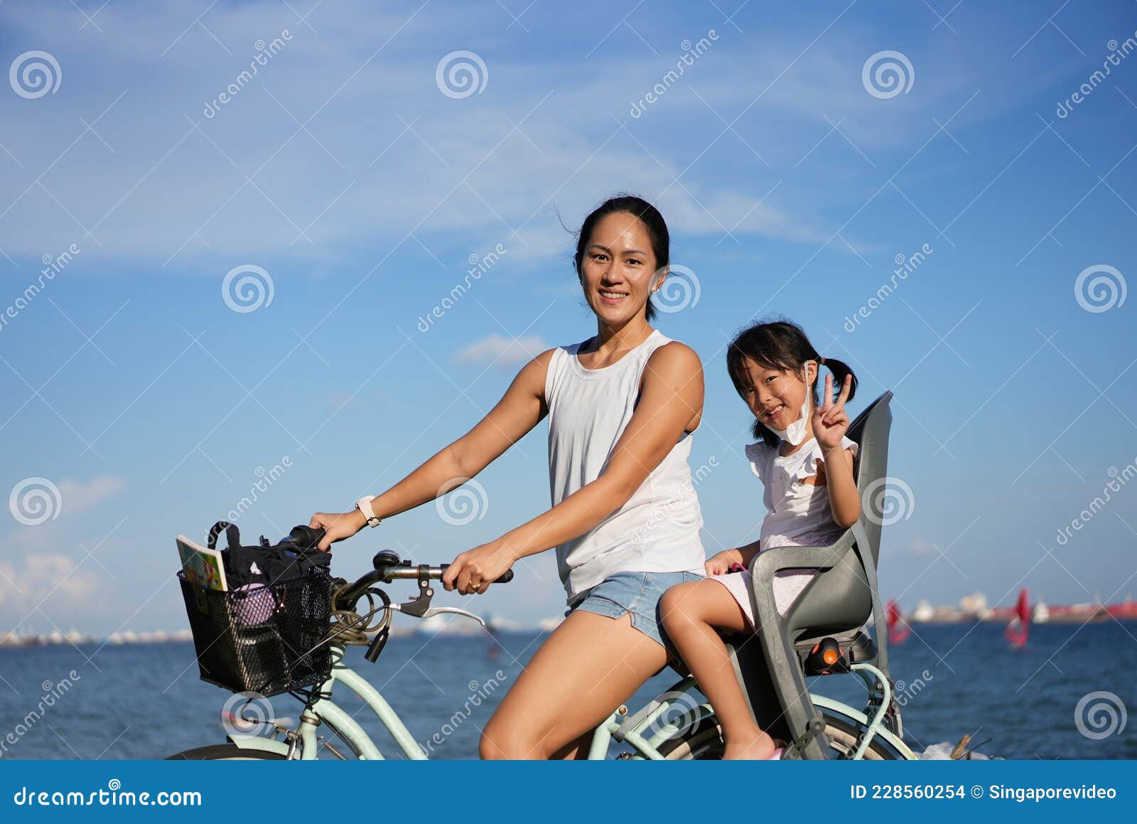 asian chinese mother and daugther cycling outdoors with covid mask