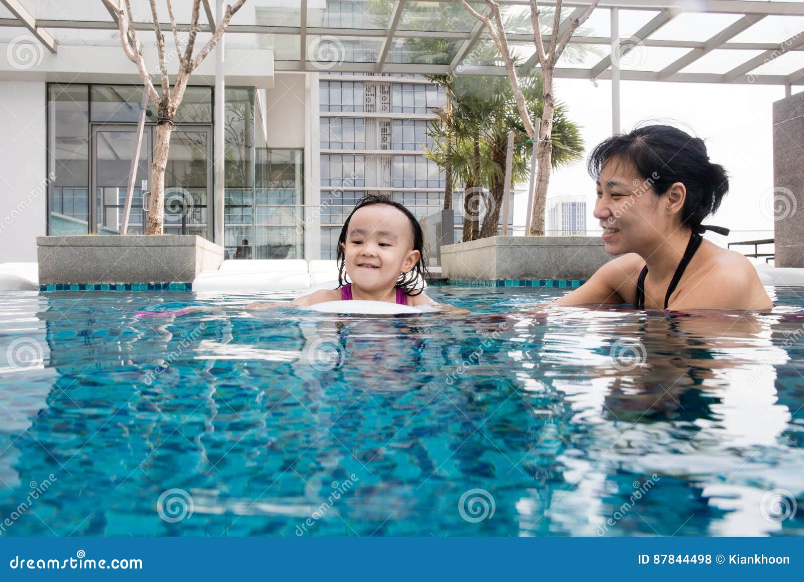 asian chinese mother and daugther playing at swimming pool