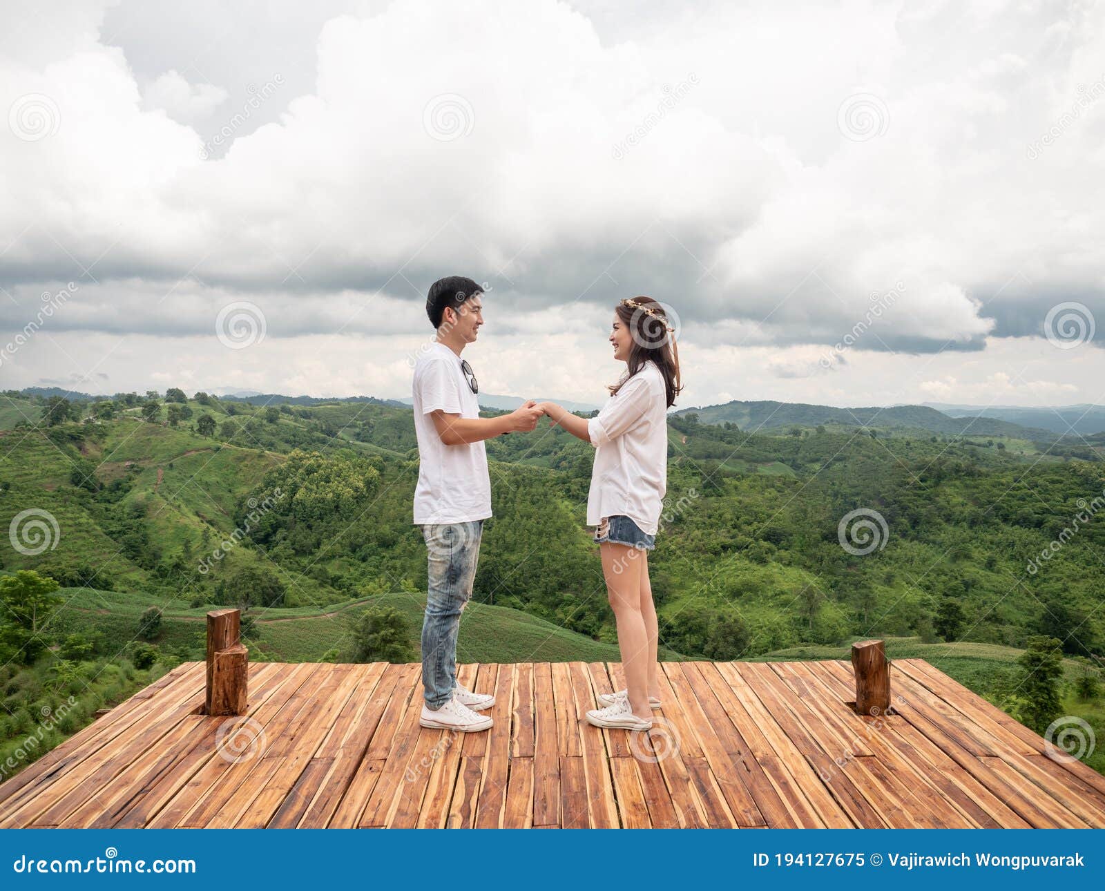 asian couple holding hands on wooden balcony with mountain view. mariage proposal concept. terrace for camping tent with landscape