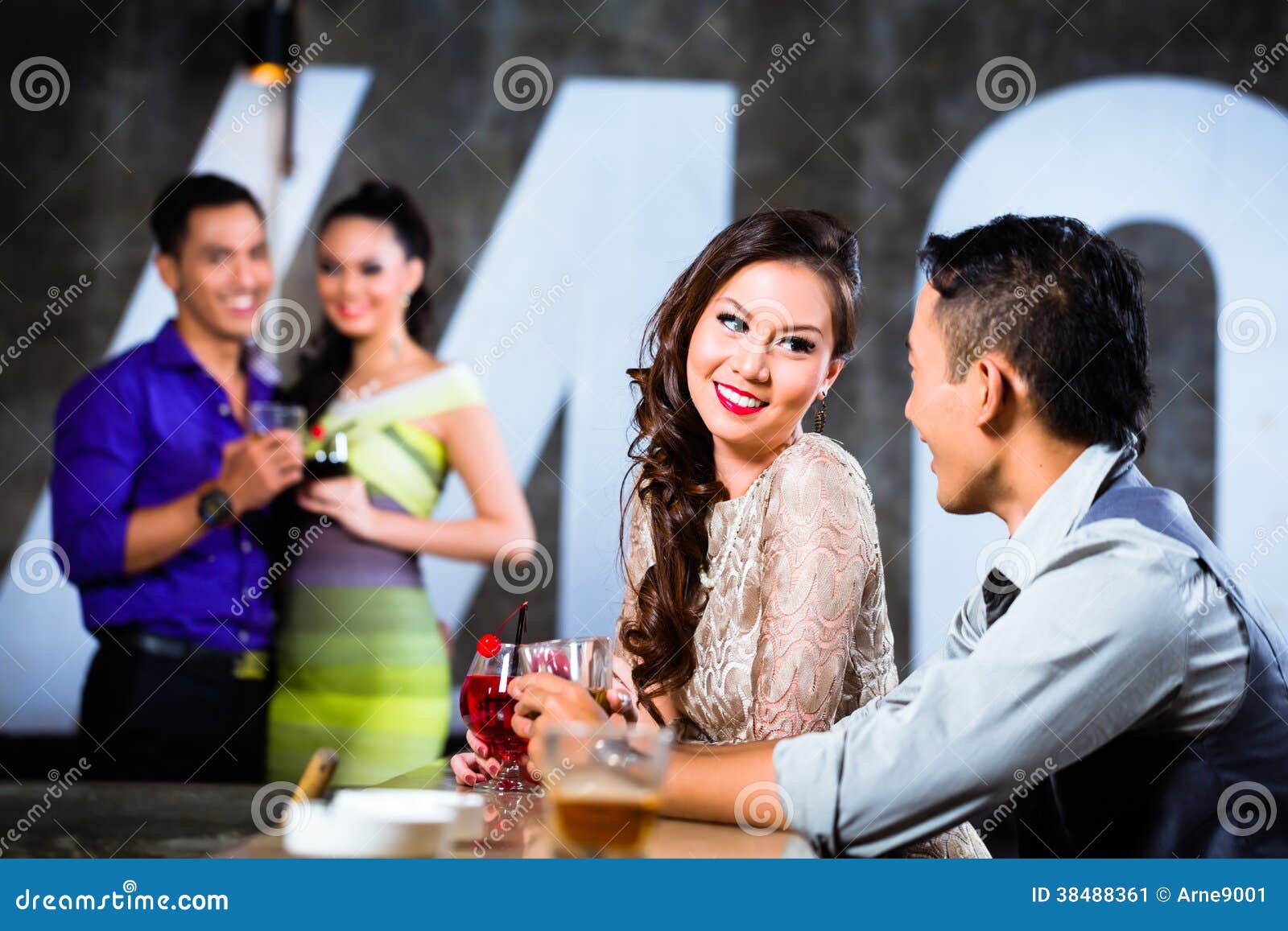 asian couples flirting and drinking at nightclub bar