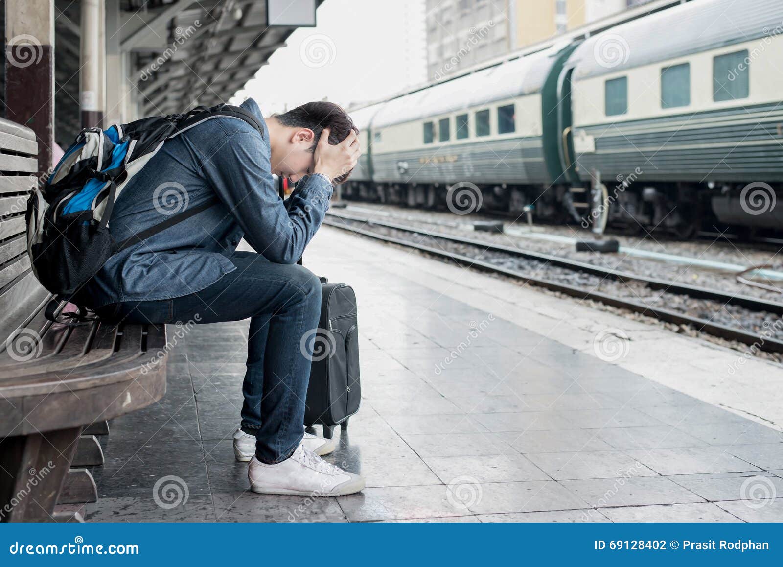 asian depressed traveler waiting at train station after mistakes