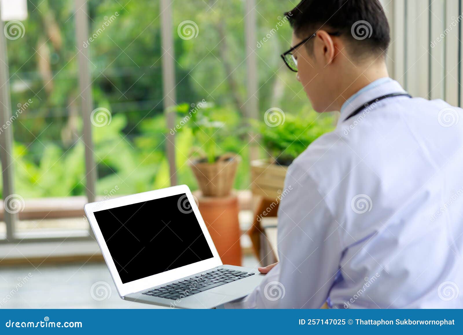 doctor man looking down at laptopp in office